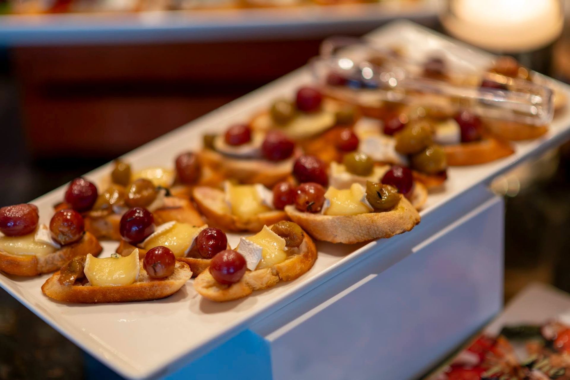 Tray of mini appetizers topped with grapes and cheese at a buffet display