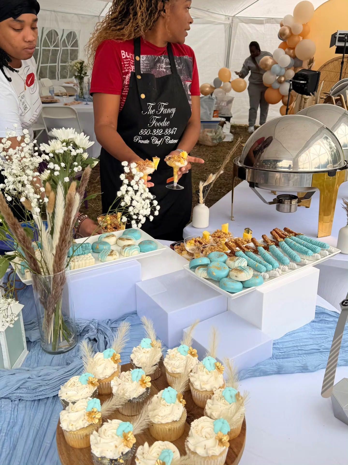Dessert buffet with cupcakes, pastries, and flowers on a table at a party