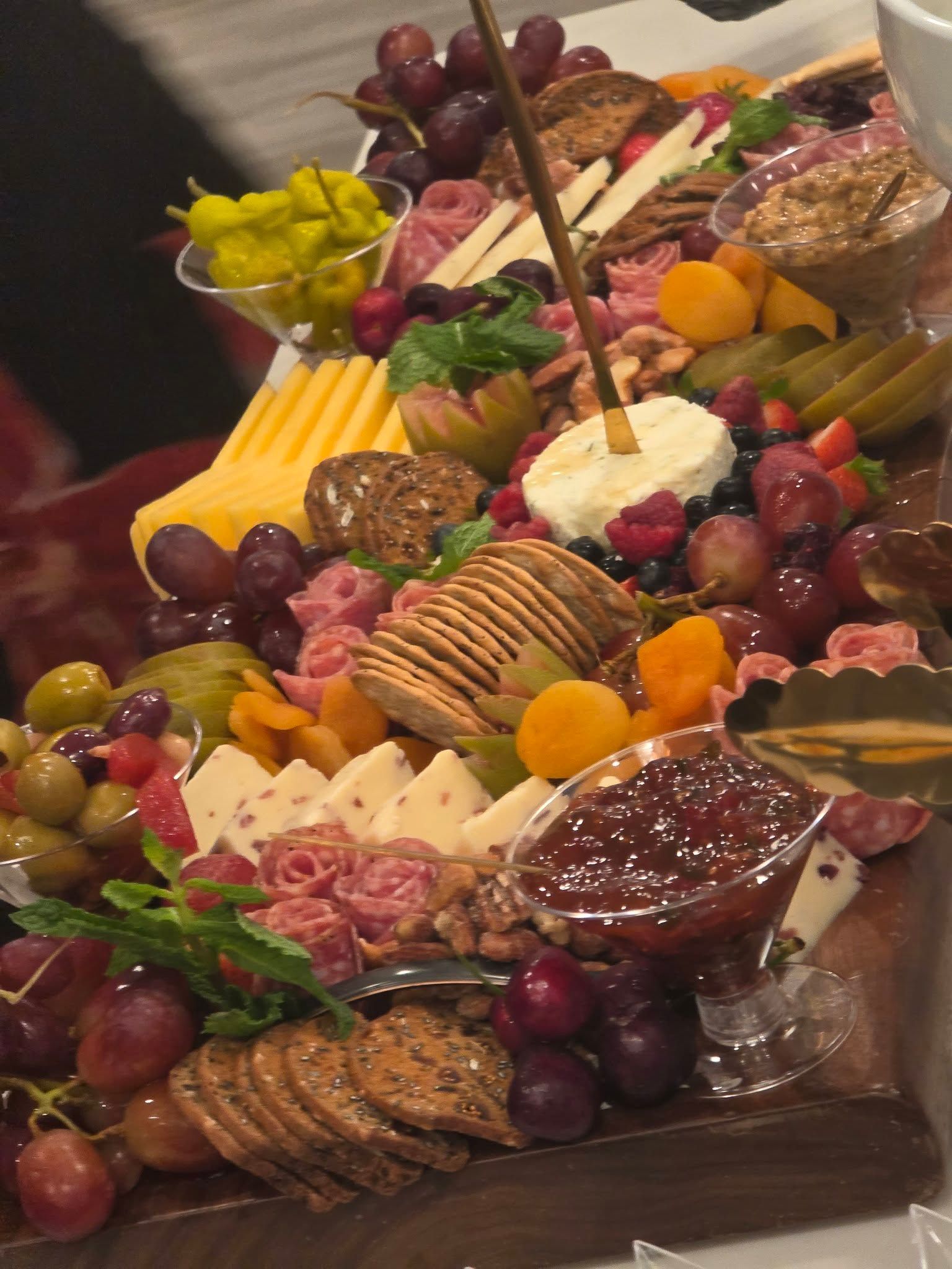 Charcuterie board with cheeses, grapes, crackers, meats, and fruit on a wooden table