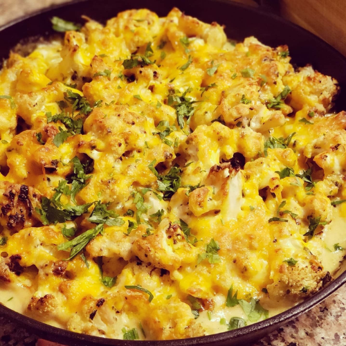Cheesy baked casserole with herbs in a round black skillet