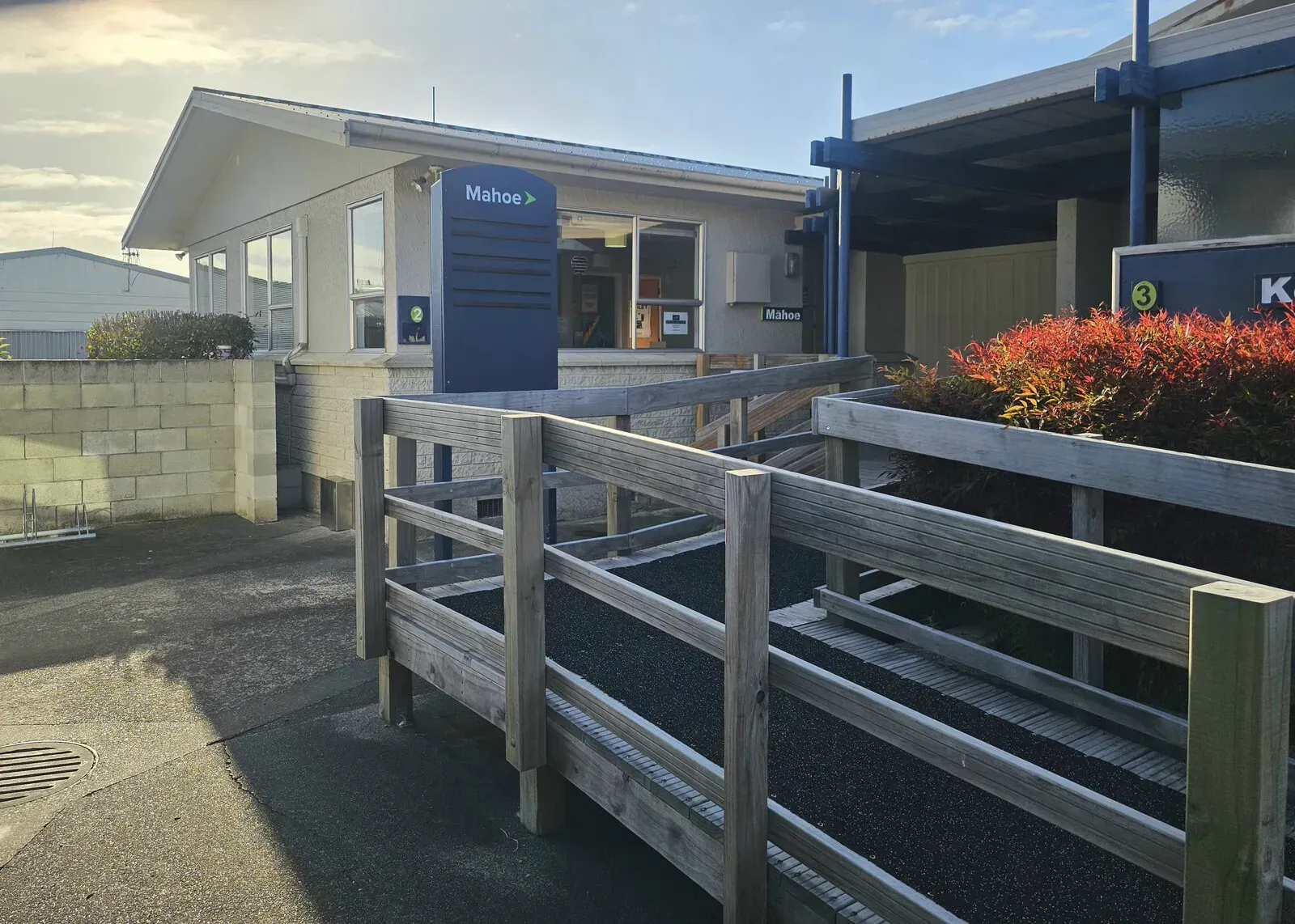 The front of the Māhoe Unit at Tamatea Medical Centre, a single-storey building with a blue sign beside a wooden ramp and handrail