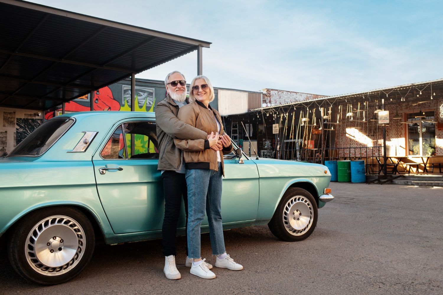 Two people standing in front of a turquoise vintage pickup truck in an outdoor market setting