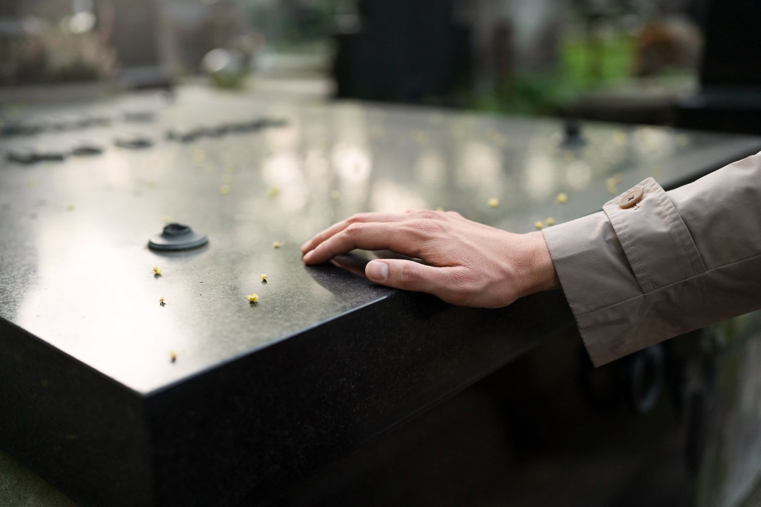 Hand resting on a wet black metal railing with a blurred waterway and walkway in the background