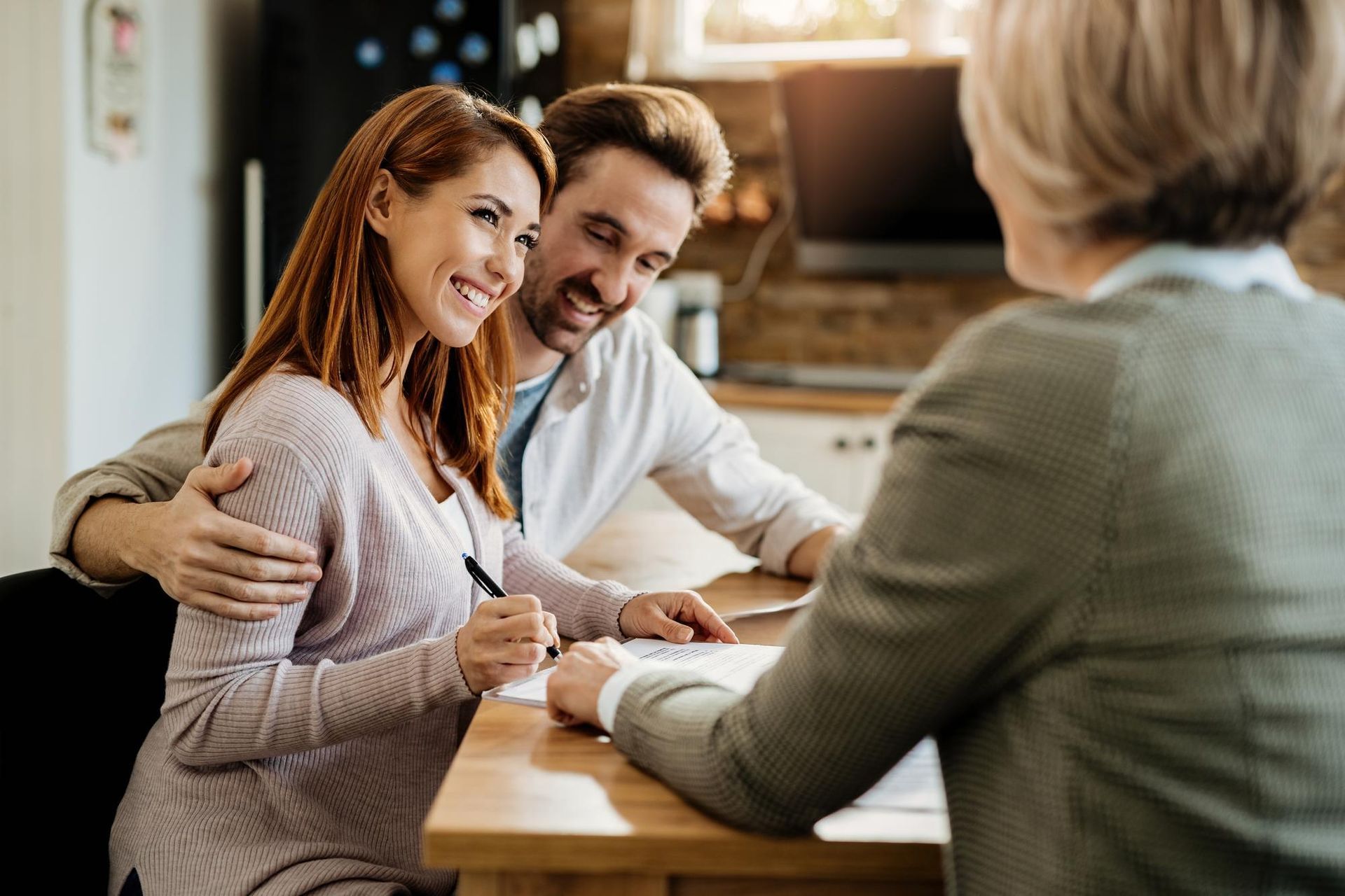 Couple smiling at a table while speaking with a counselor in a cozy office