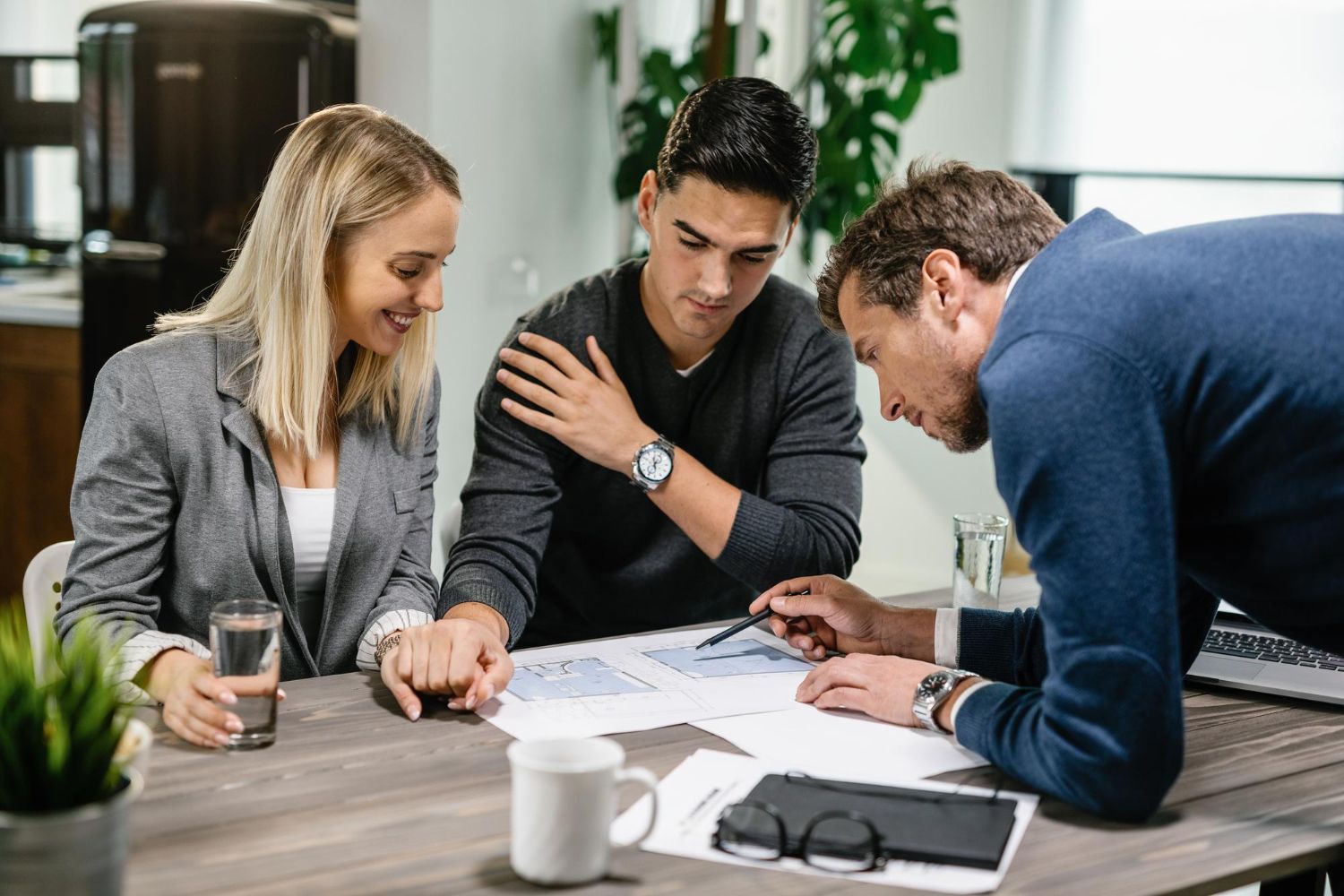 Three coworkers reviewing documents at a table in a bright office meeting room