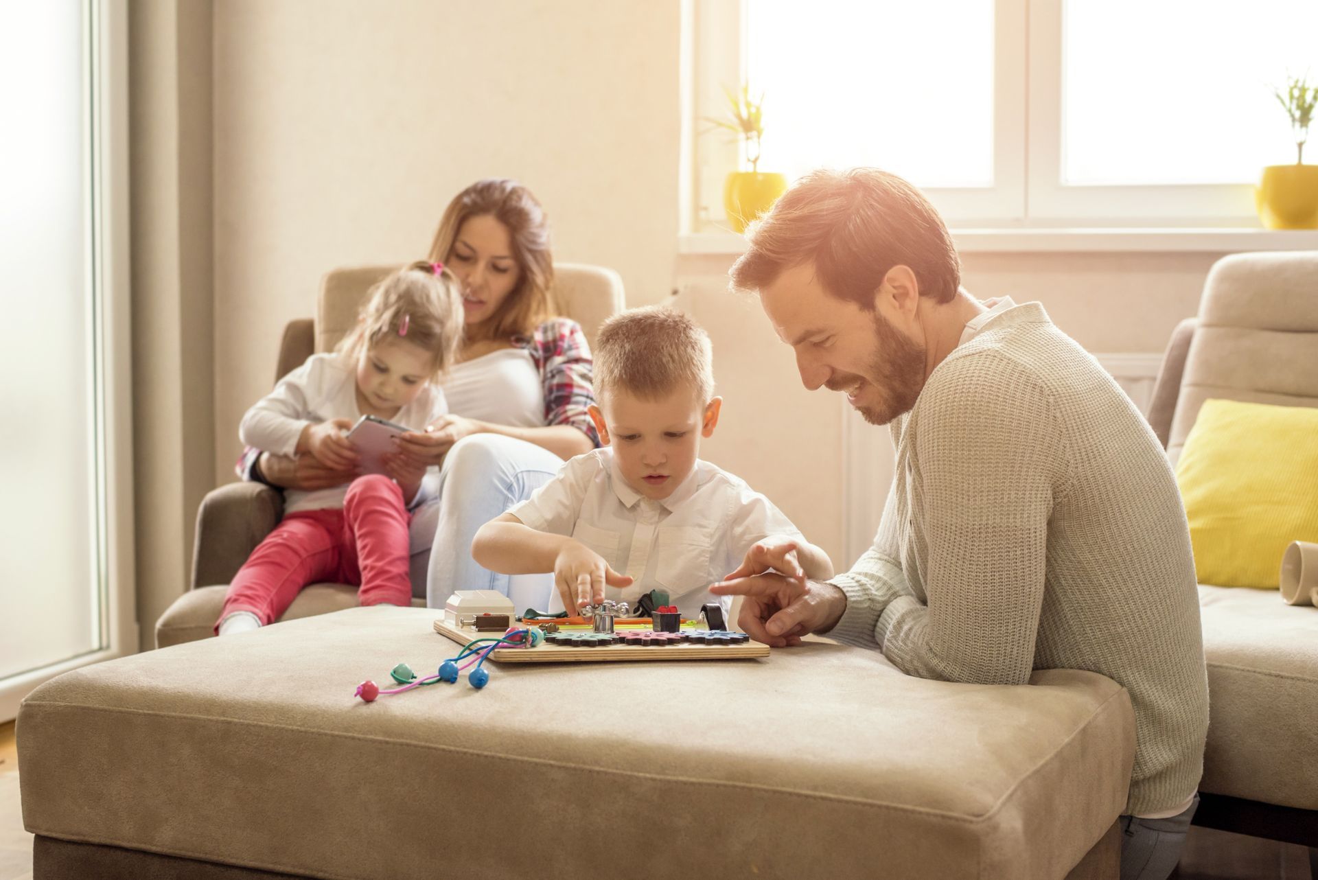 Family playing a board game on a couch in a bright living room