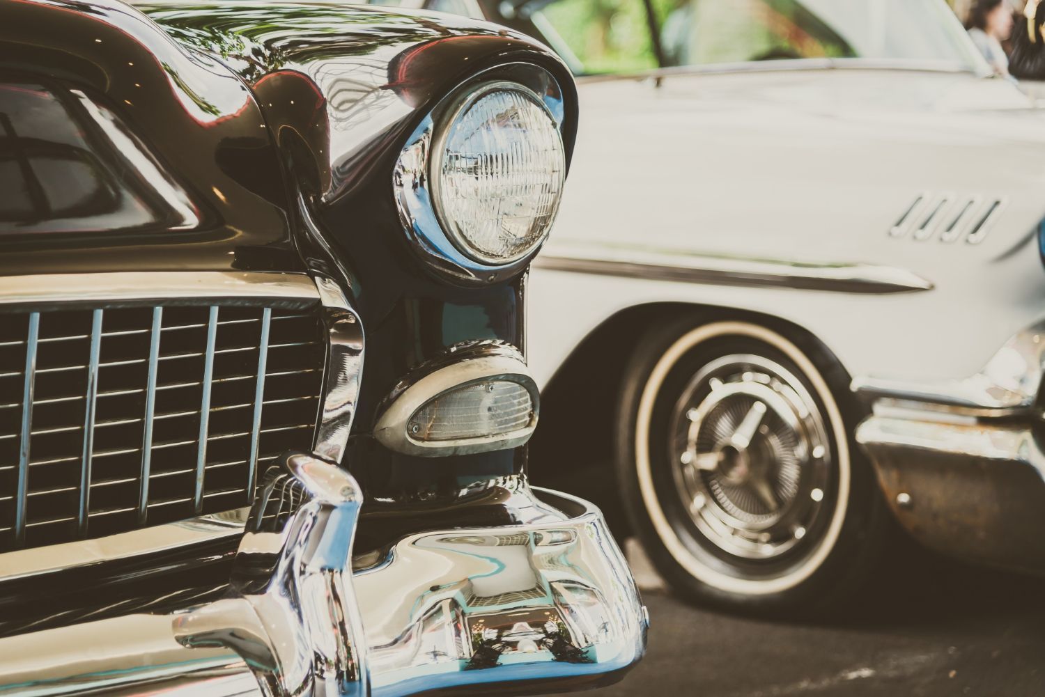 Close-up of vintage classic cars, with chrome grille and headlights in the foreground