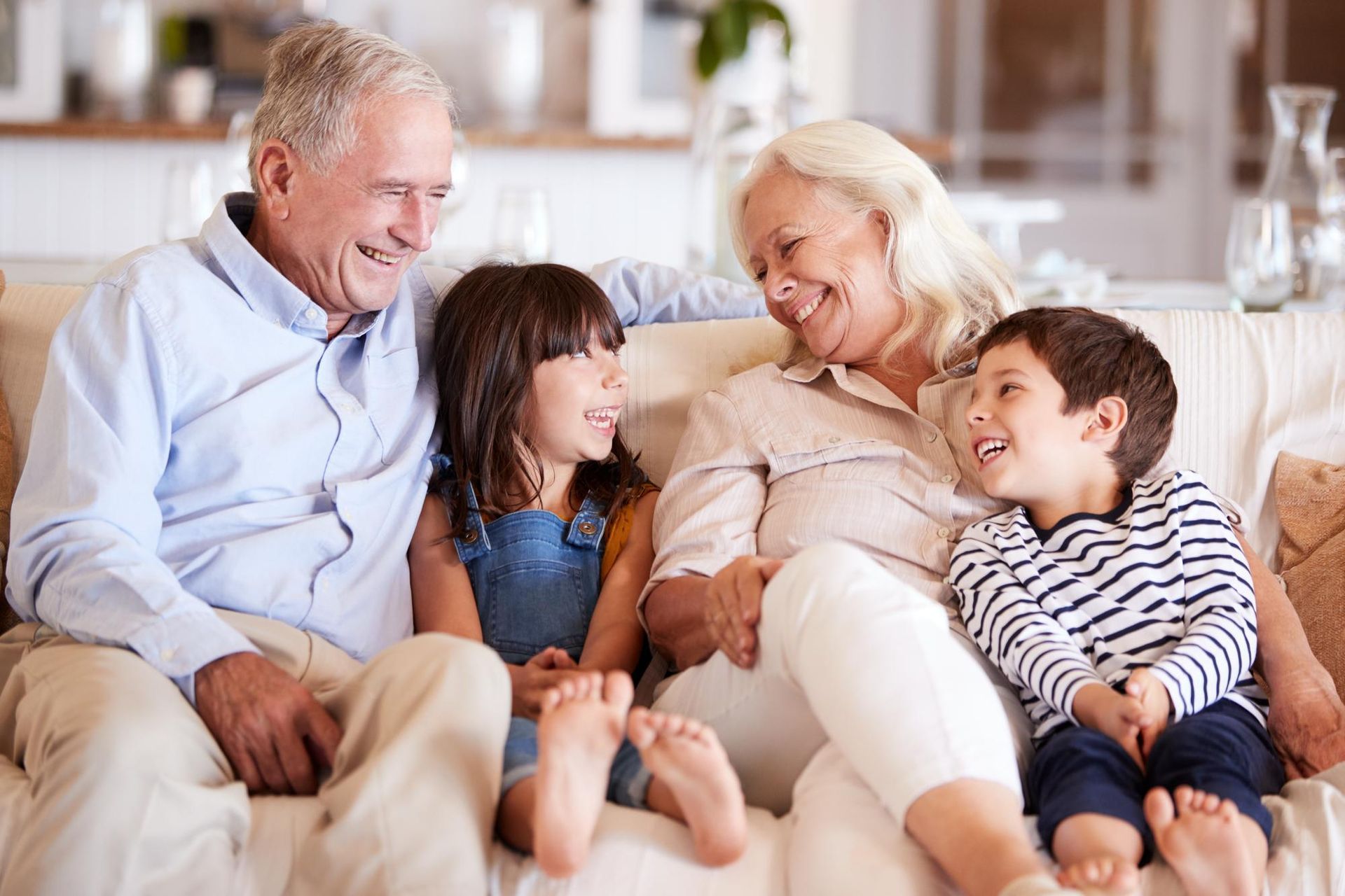 Family sitting together on a couch, smiling and laughing in a cozy living room