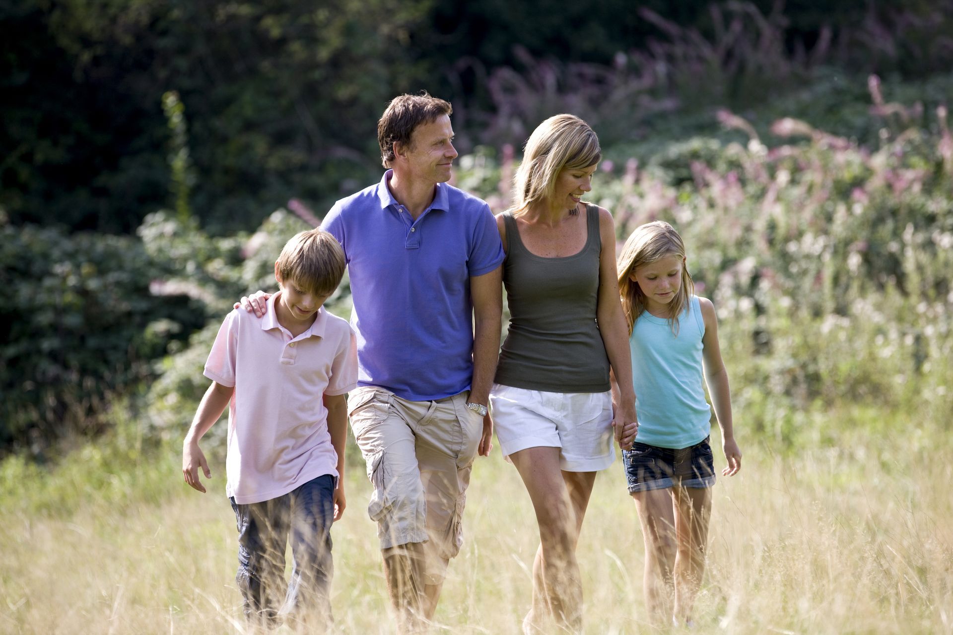 Family walking together through a sunlit grassy field