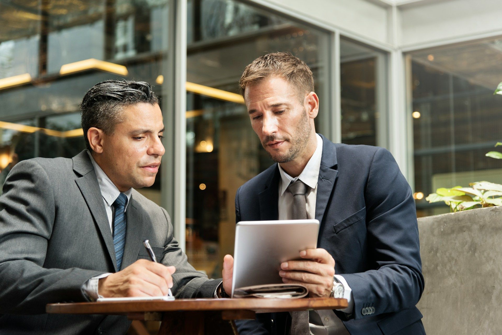 Two professionals reviewing a laptop together at a table in a modern office.