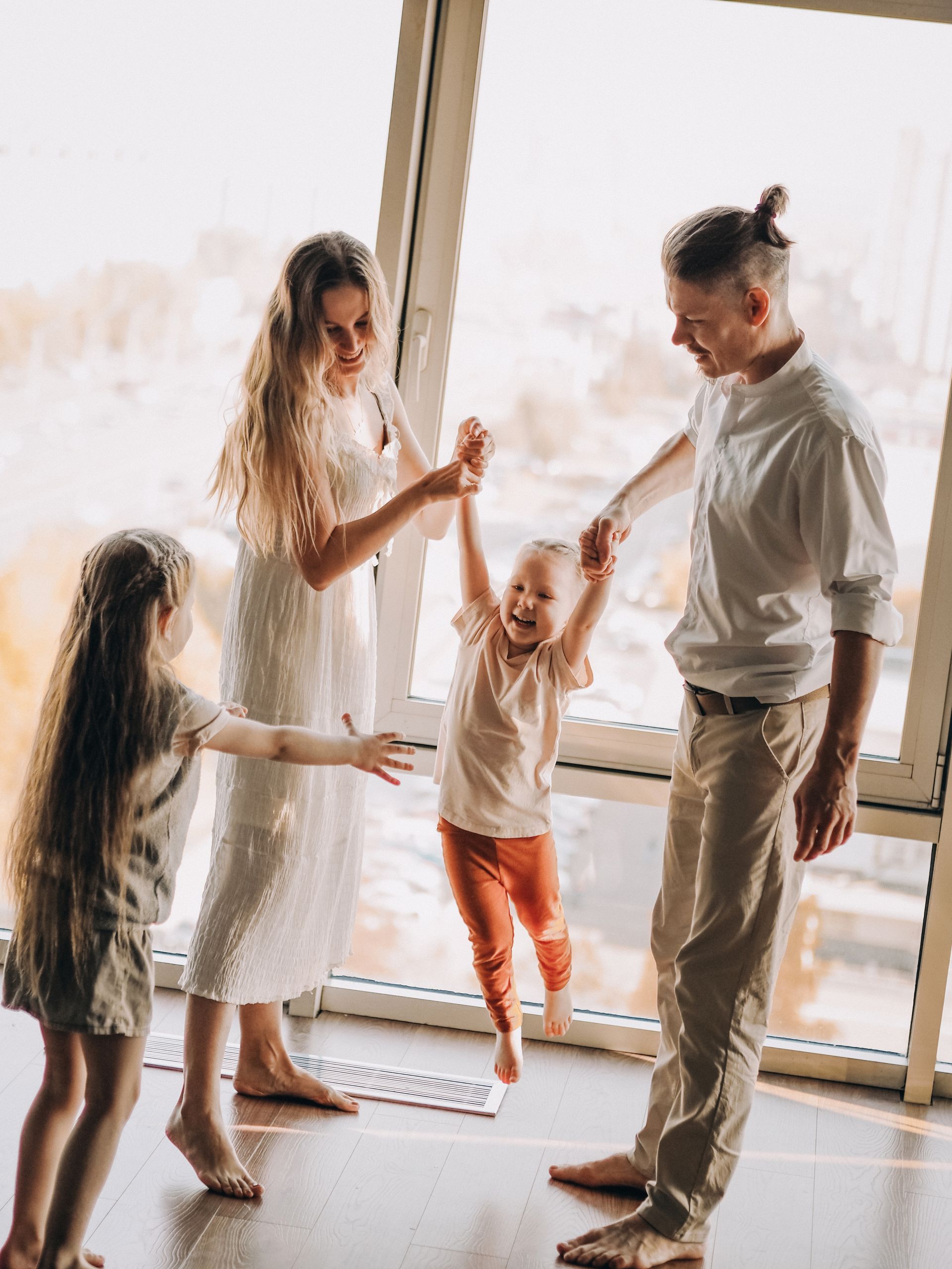 Family dancing together in a bright living room near a large window