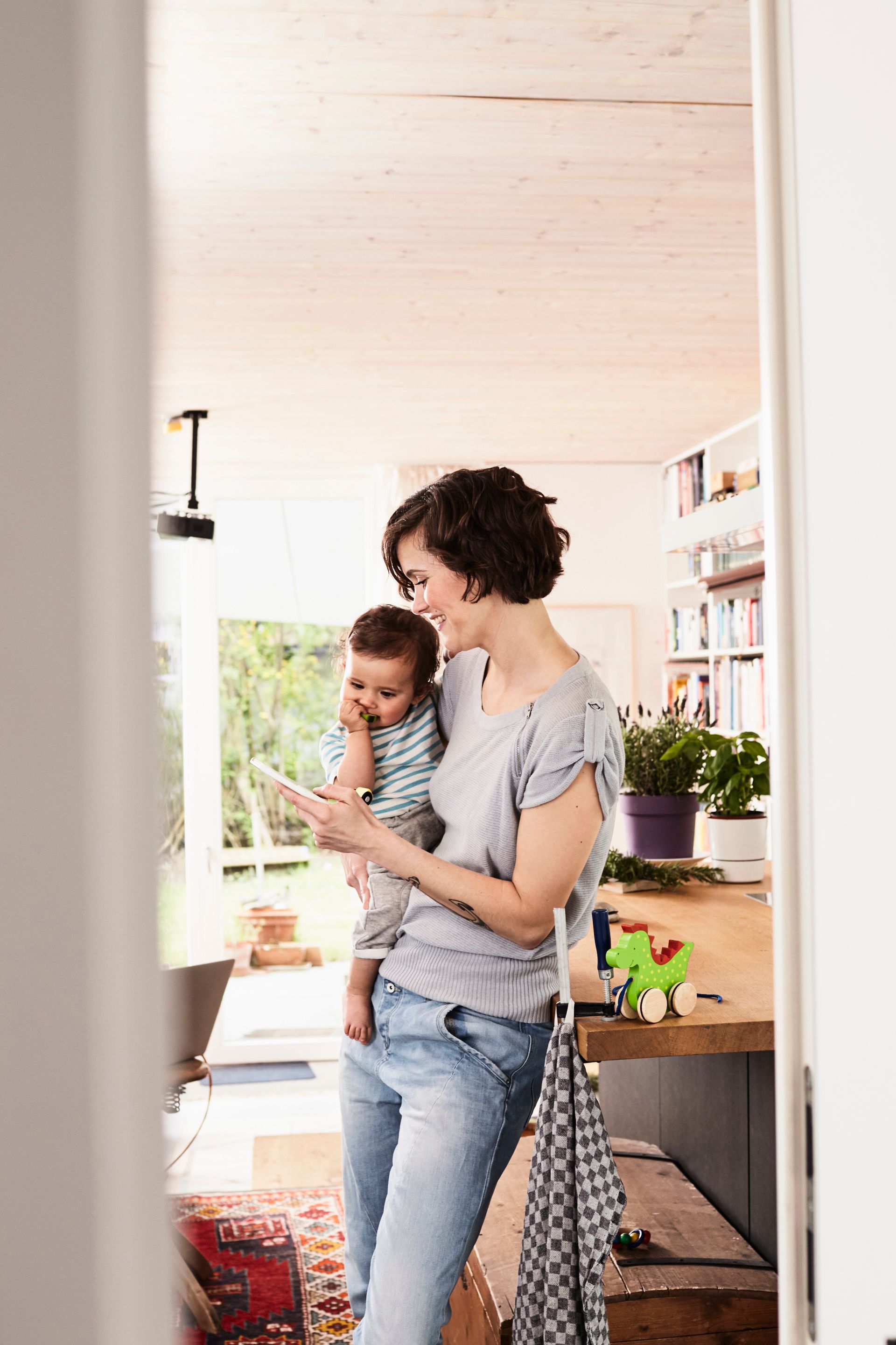 Woman holding a child in a bright kitchen doorway