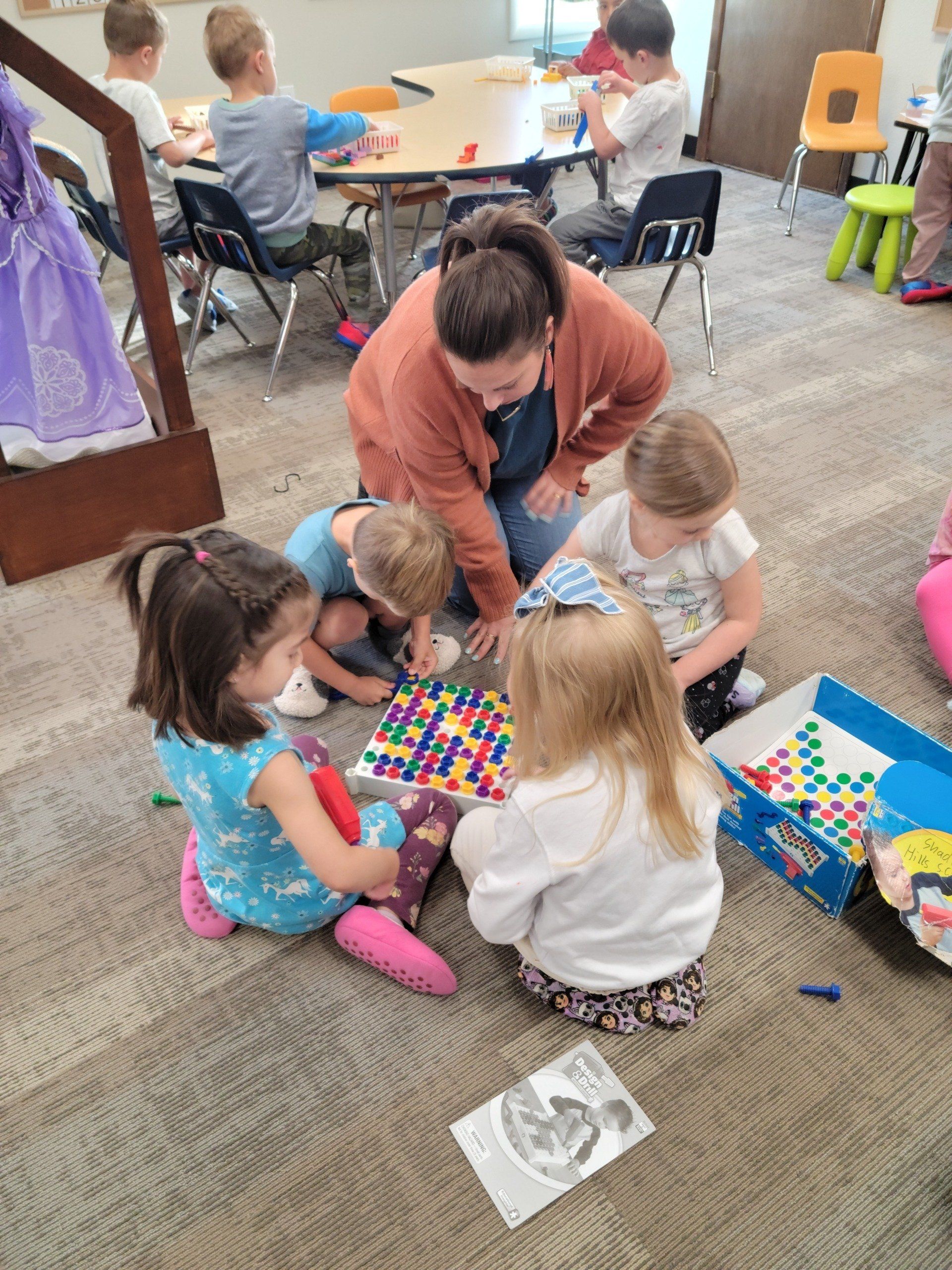 A group of children are sitting on the floor playing with toys.