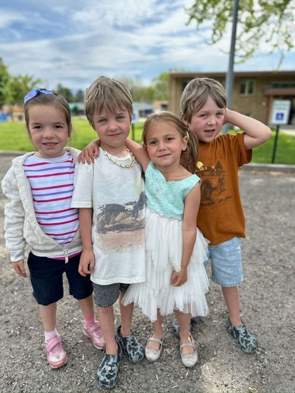 Three children are standing next to each other holding magnifying glasses and flowers.
