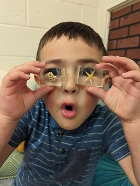 A young boy wearing a pair of 3d glasses is sitting at a table.