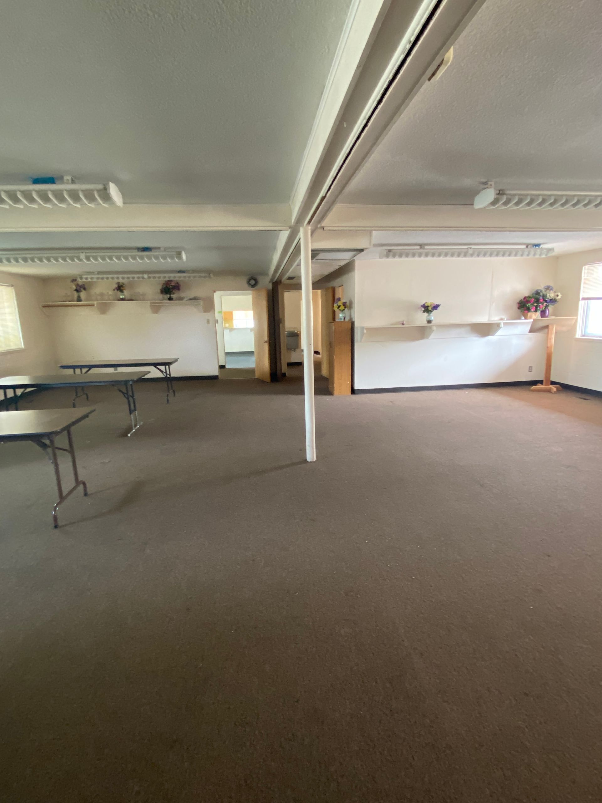 A large empty room with tables and chairs in it.