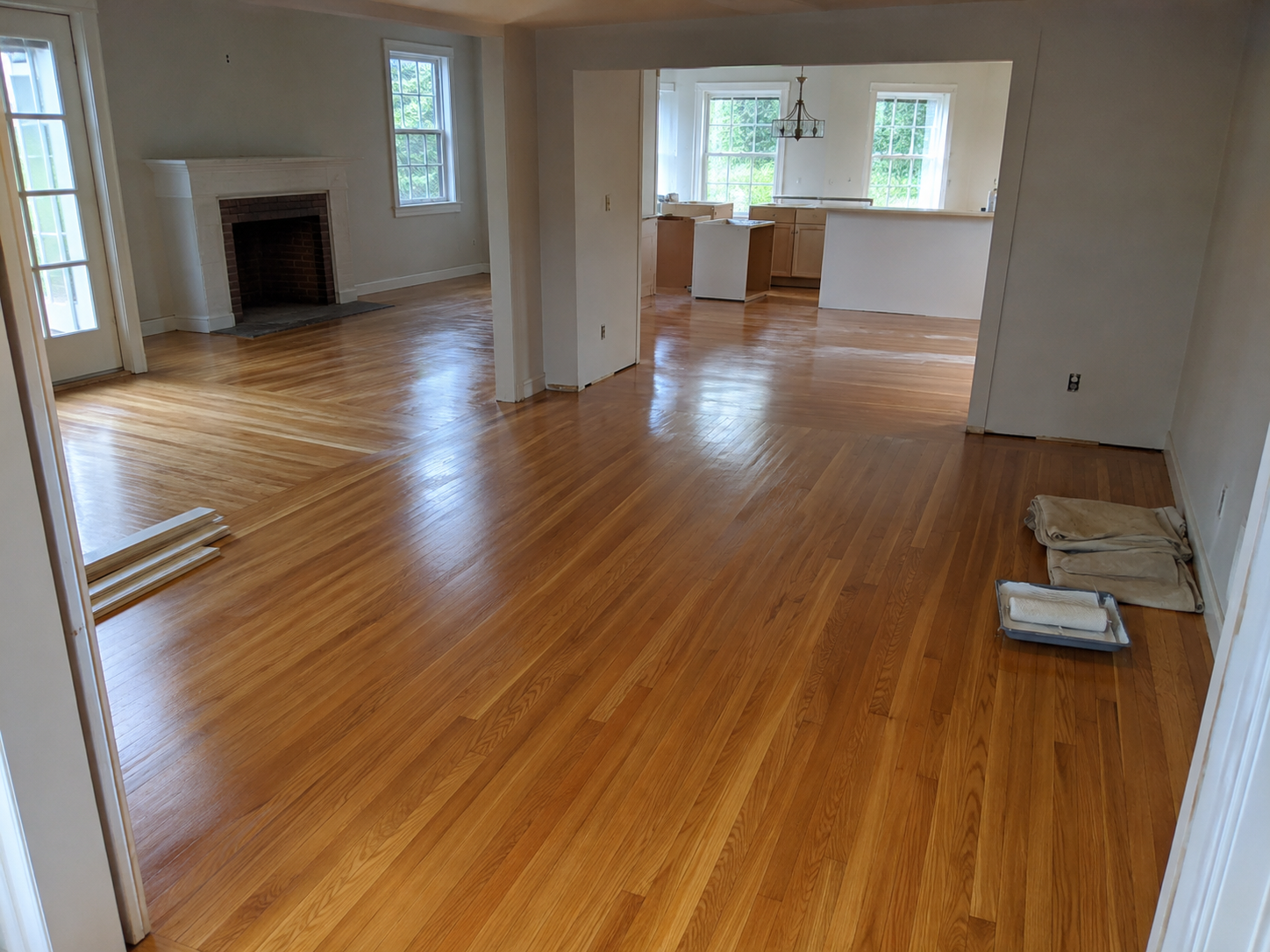 Empty living room with hardwood floors, fireplace, and open kitchen area