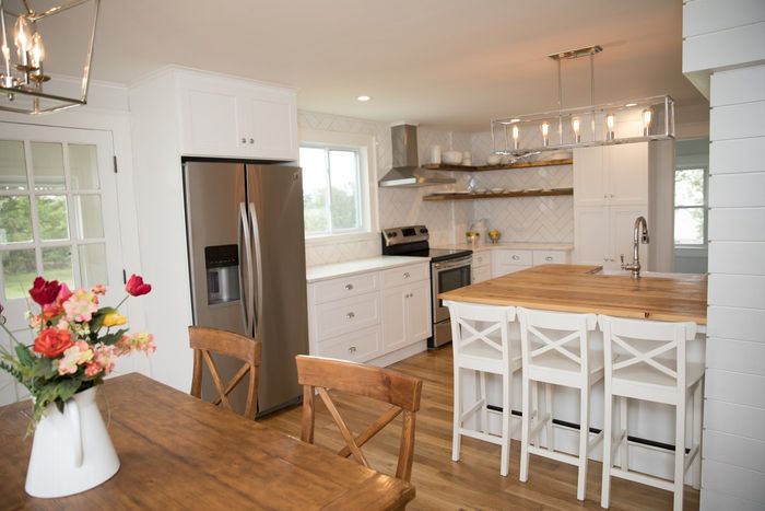 Modern kitchen with stainless steel appliances, white cabinets, wooden island, and dining table.