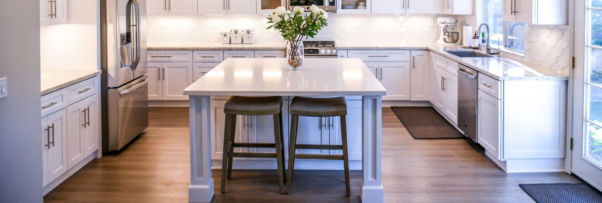white kitchen with an island, and hardwood floors installed