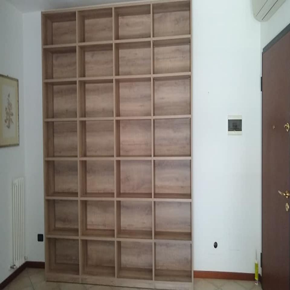Scaffalatura a muro in legno vuota, appoggiata a una parete bianca in una stanza.