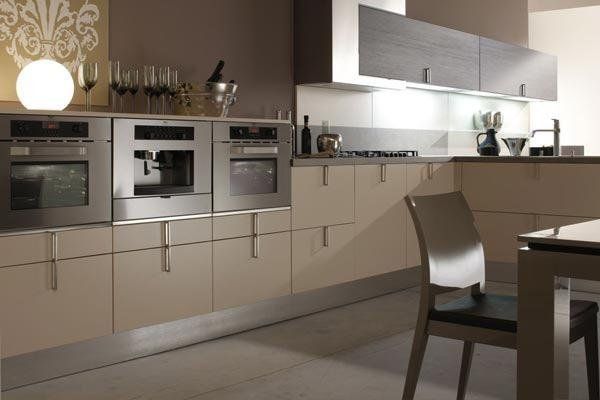 Cucina moderna beige con forni a incasso, ripiani e una sedia da pranzo in primo piano.