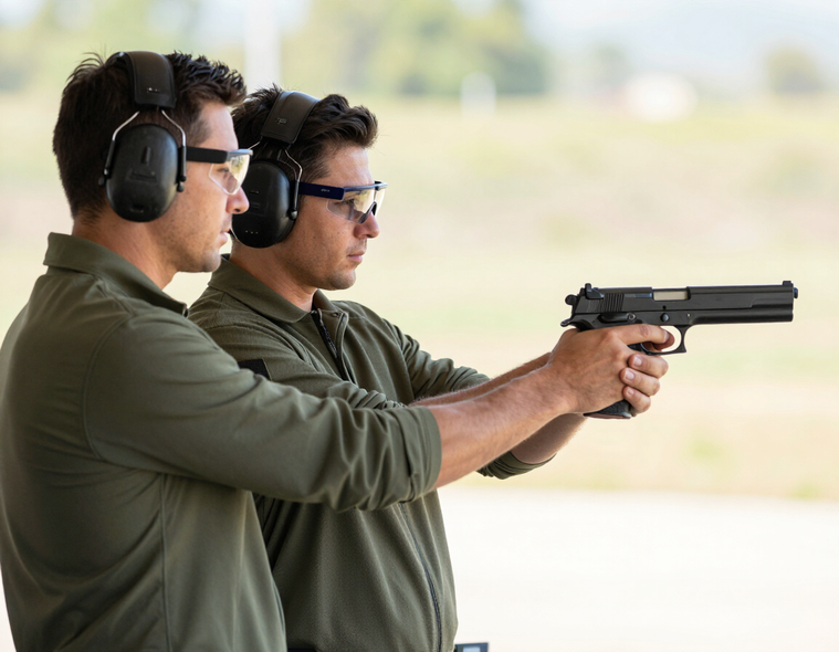 Instructor guiding a student in safe firearms handling