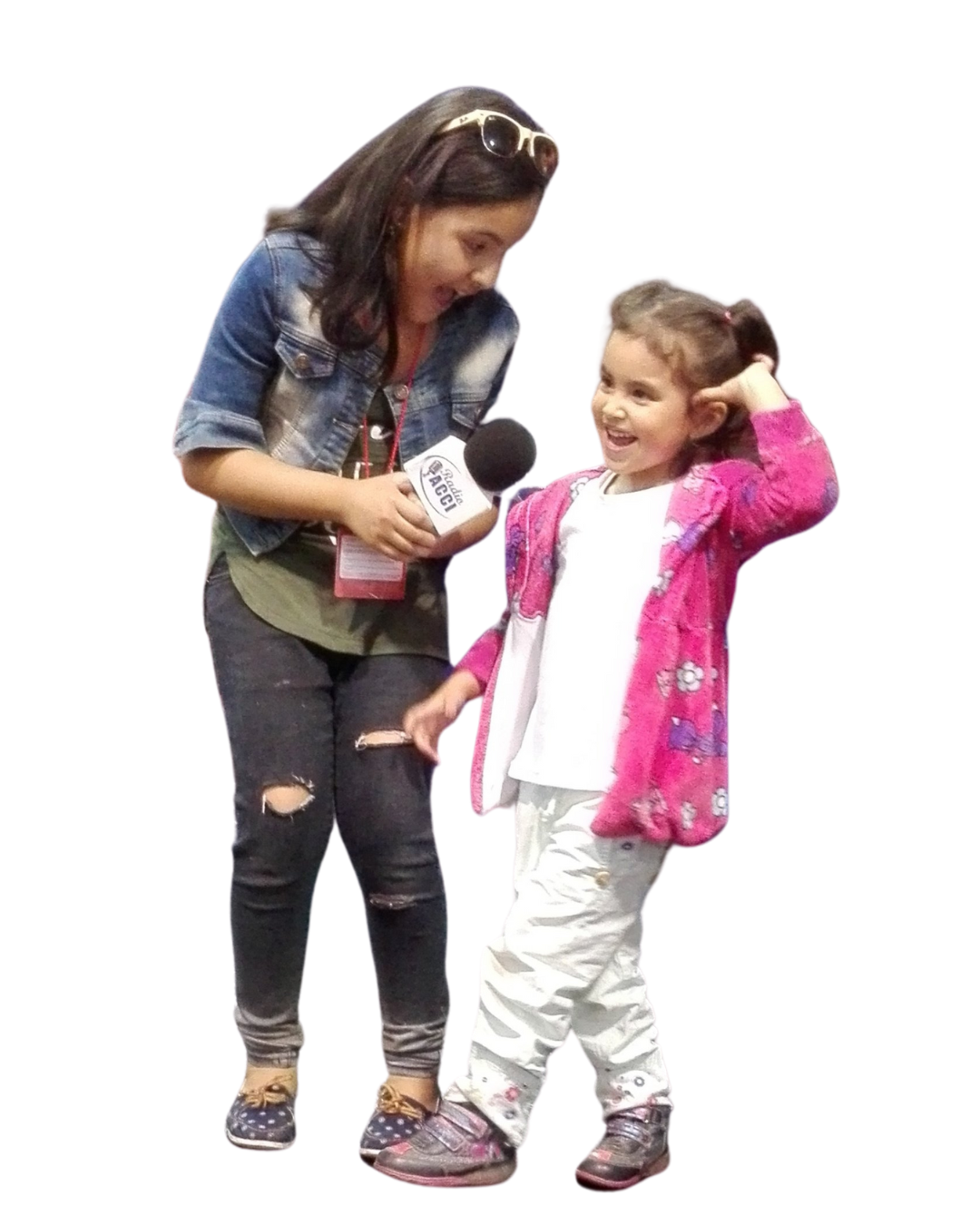 Niña entrevistando a un niño con un micrófono; el niño hace gestos juguetones.