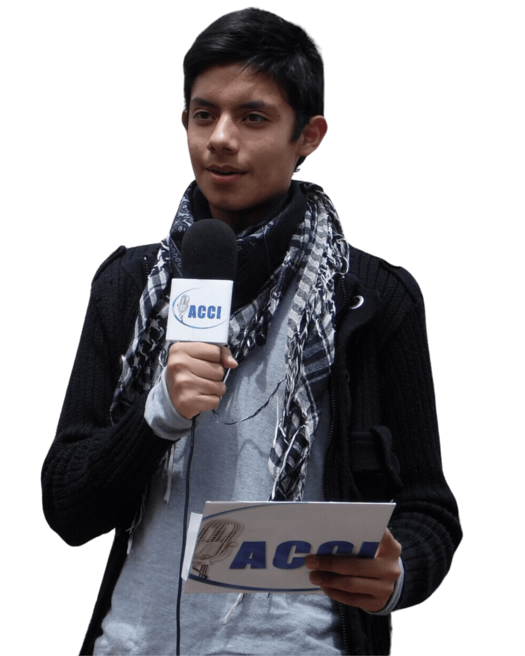 Persona con micrófono y papel; un reportero. Lleva bufanda y chaqueta, hablando.