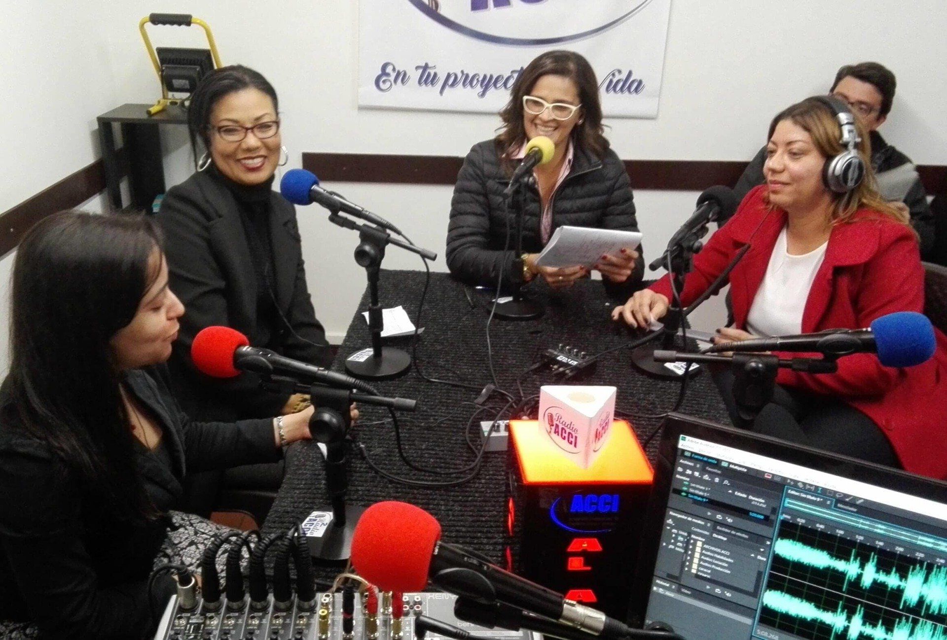 Mujeres en una emisora ​​de radio grabando un podcast. Micrófonos, mesa de mezclas, sonriendo, hablando.