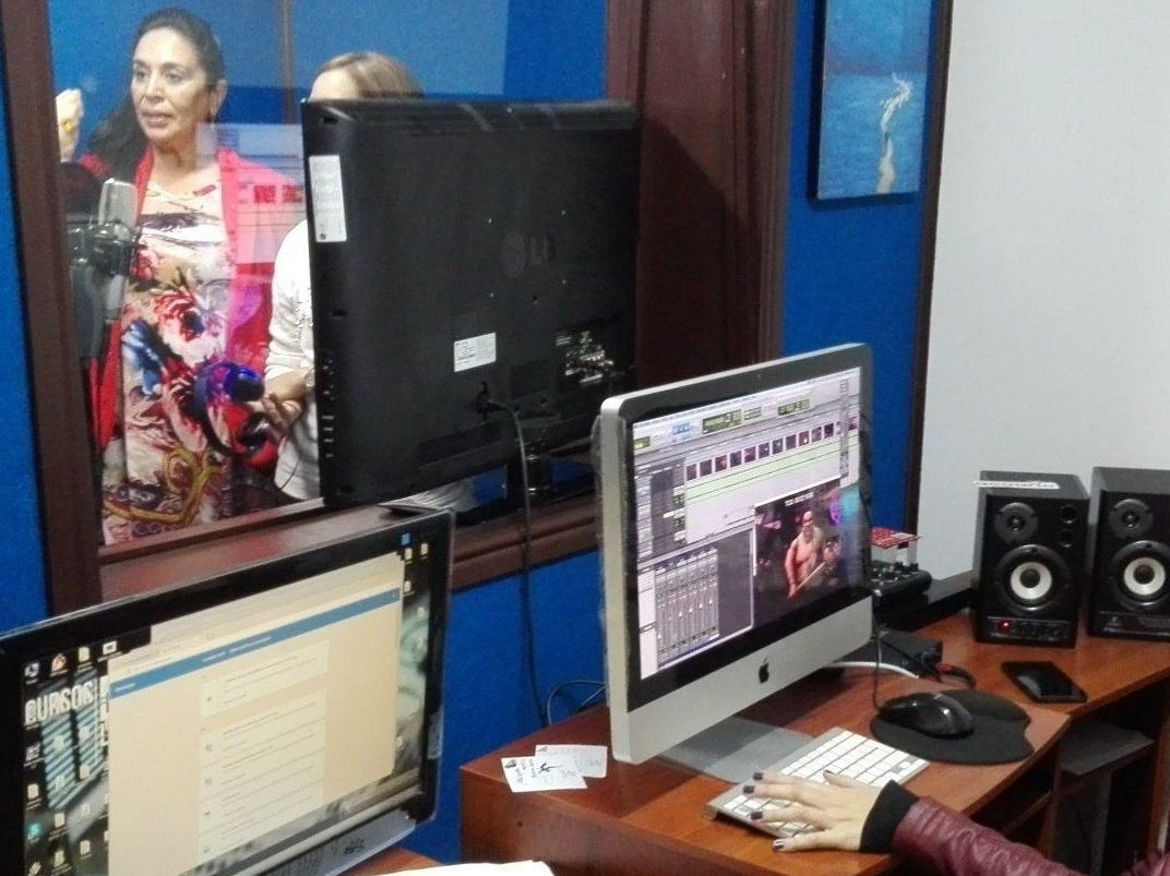 Mujer trabajando con una computadora en una oficina, con el reflejo de otra mujer en la ventana.