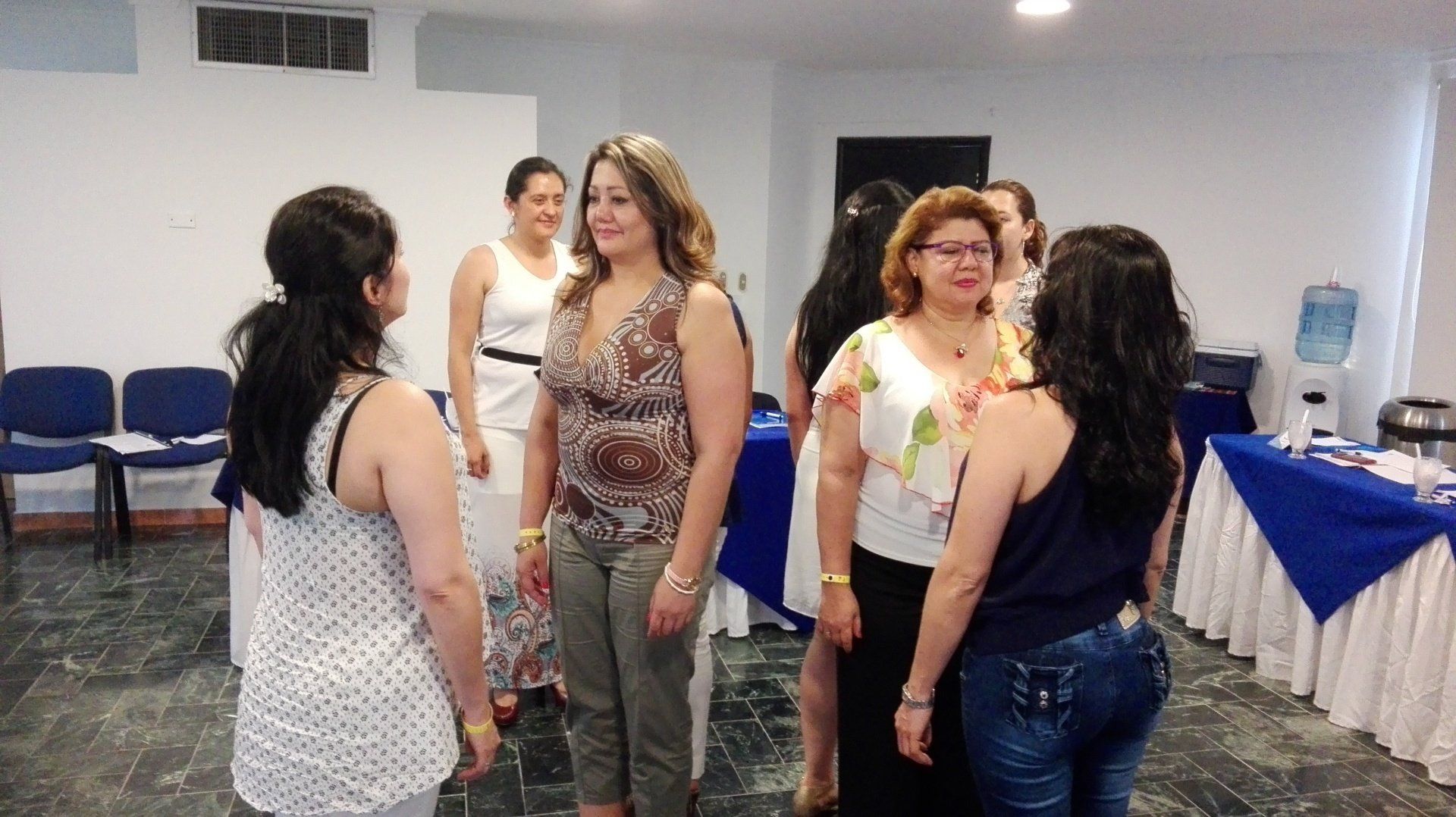 Un grupo de mujeres en una habitación, algunas enfrentadas, posiblemente en un taller o reunión.