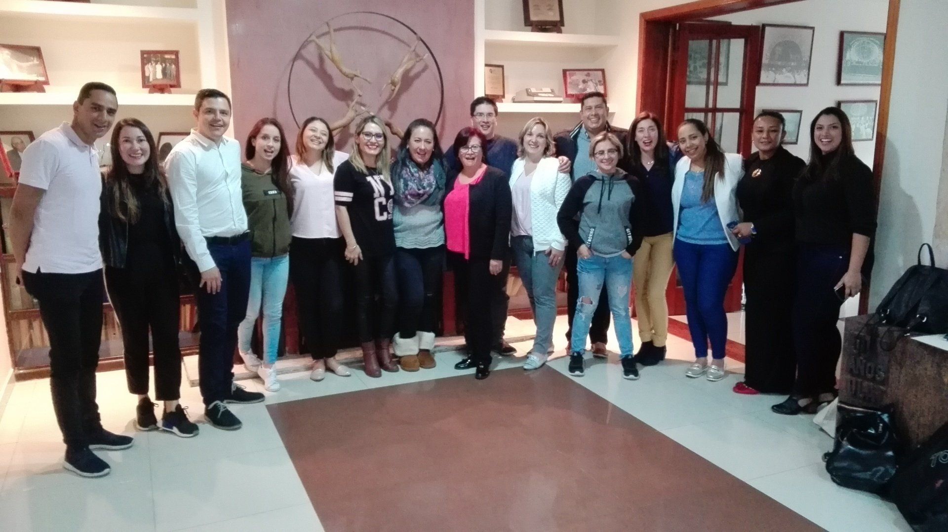 Grupo de personas posando en una habitación. Sonríen y miran a la cámara. Fondo neutro.