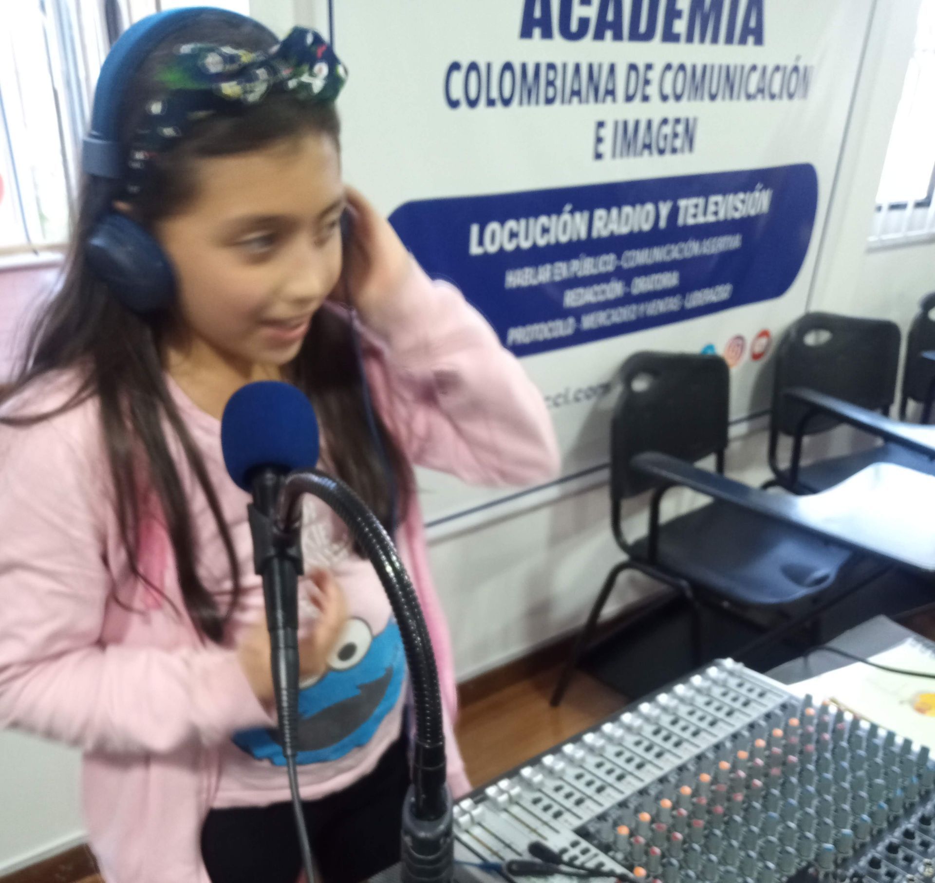 Una chica con auriculares y micrófono en un estudio de radio sonríe.