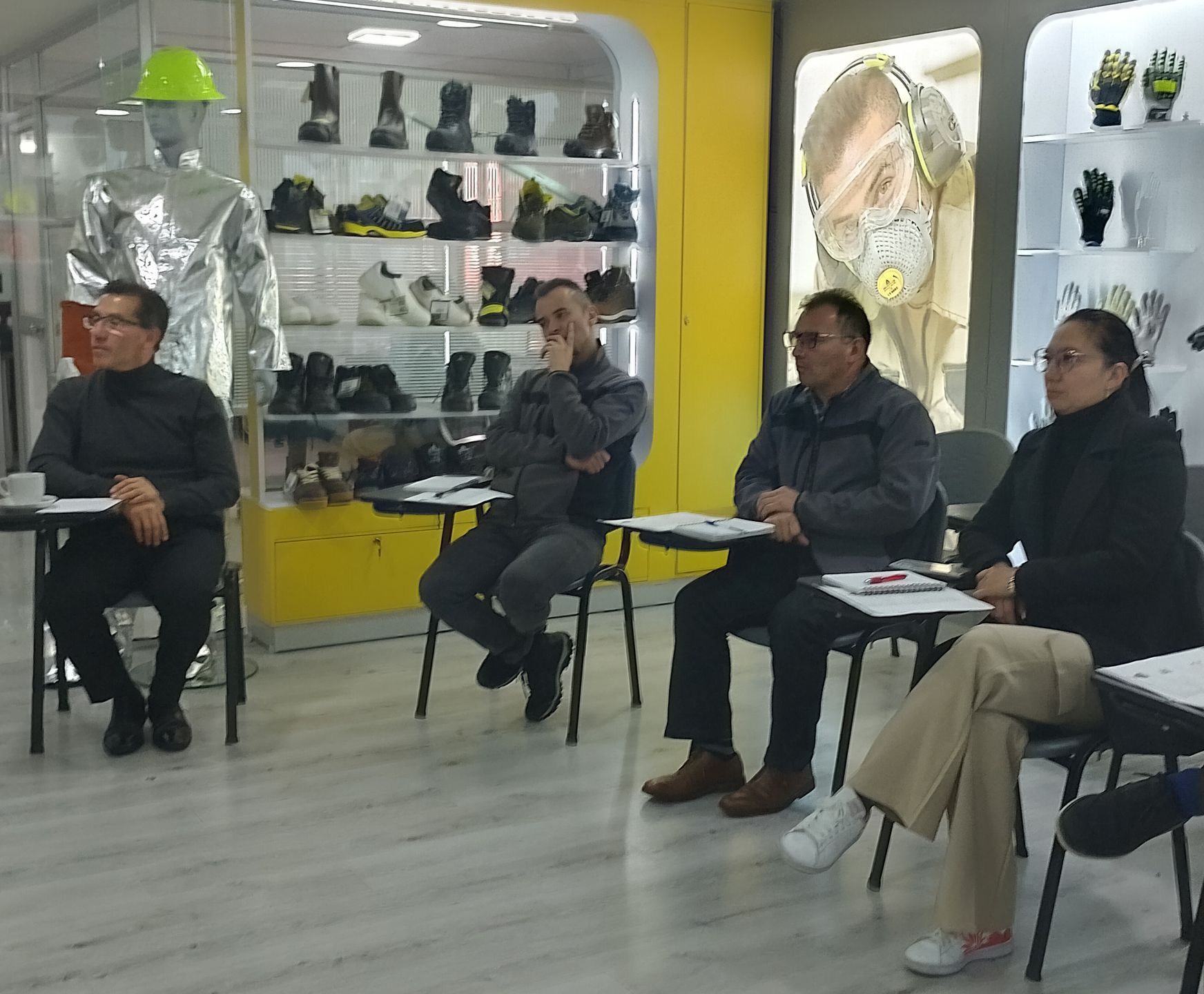 Cuatro personas sentadas en escritorios, posiblemente en una reunión, en una tienda de equipos de seguridad.