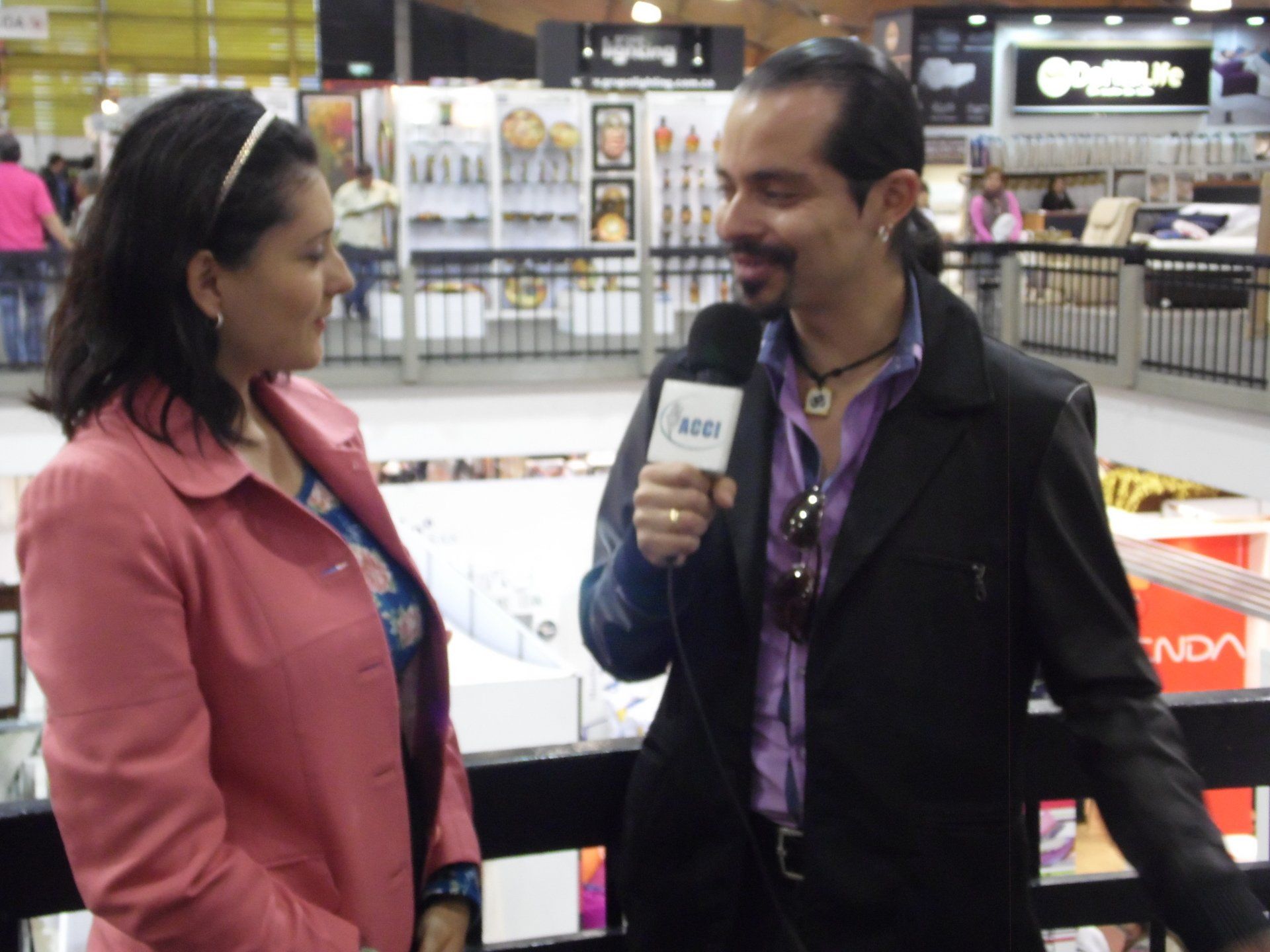Mujer con chaqueta rosa siendo entrevistada por un hombre con micrófono.