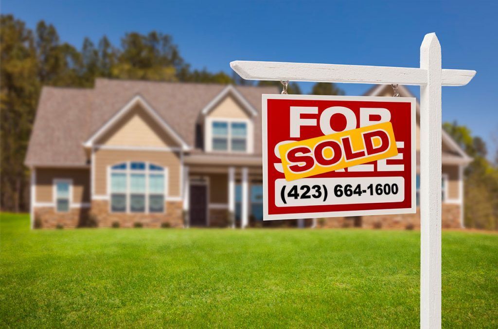 A for sale sign is in front of a house.