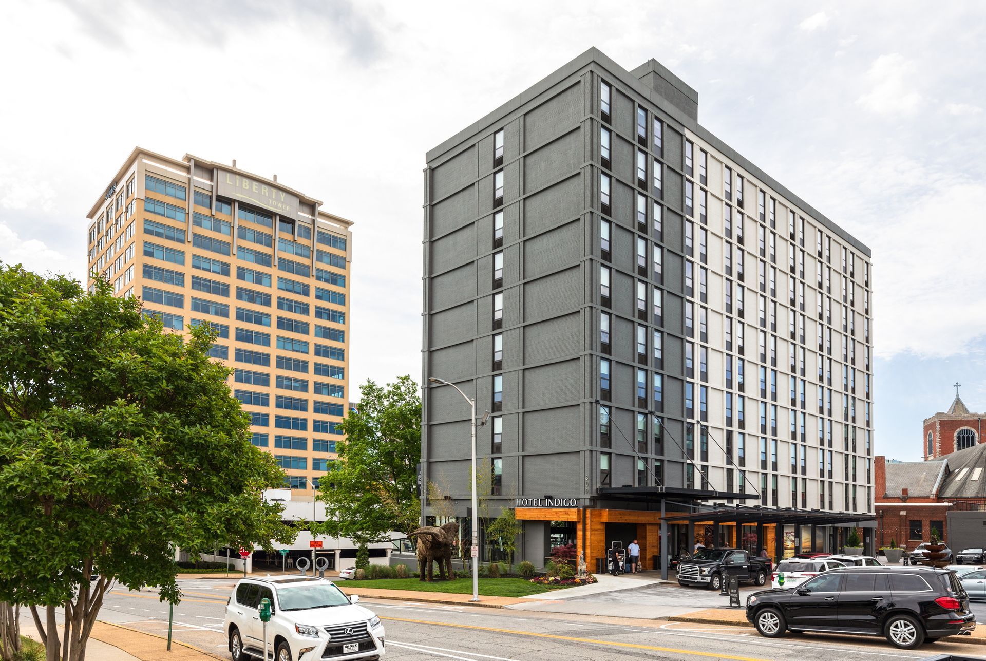 A large building with a lot of windows is sitting on the corner of a city street.