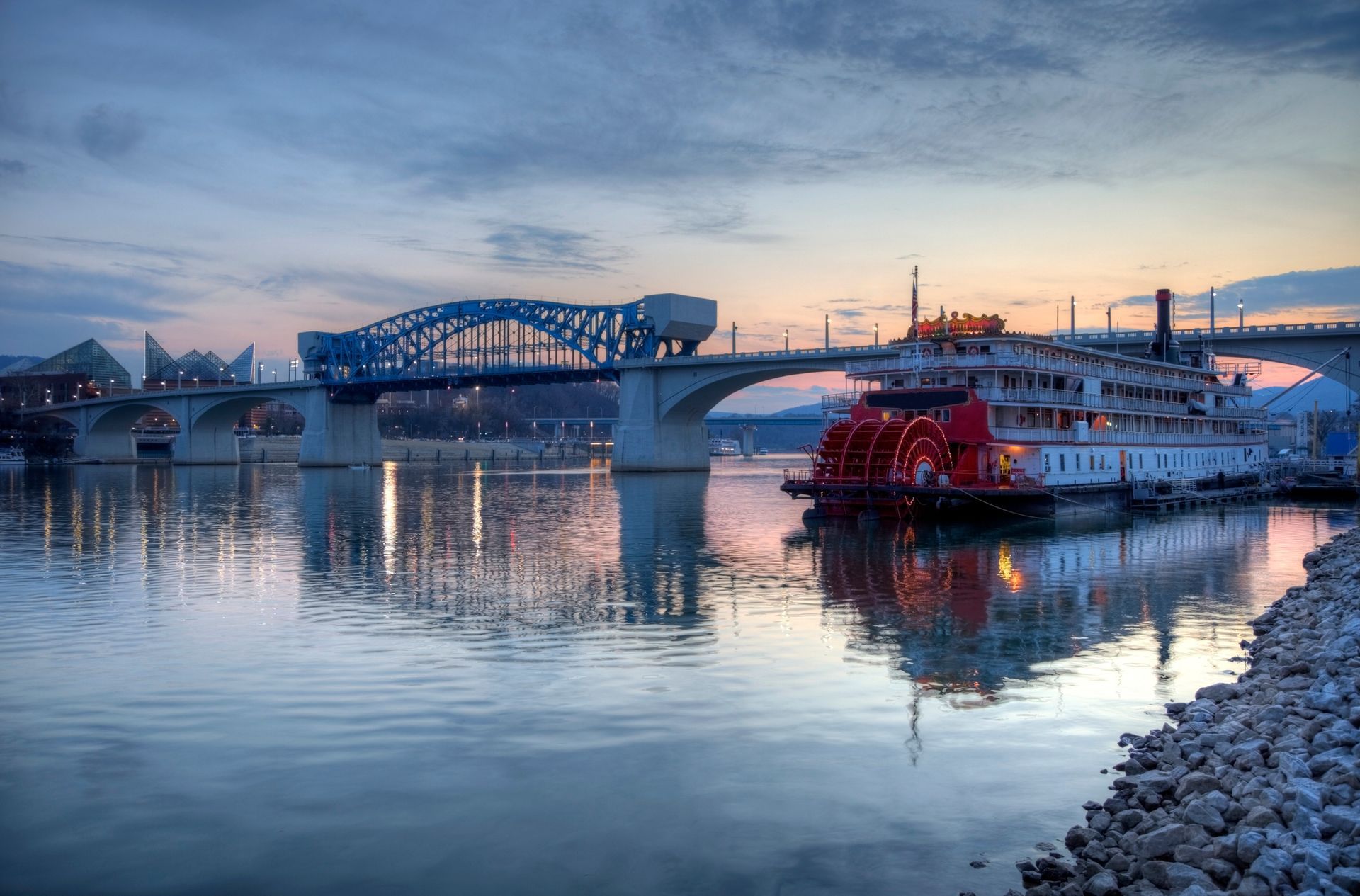 A boat is docked under a bridge over a body of water.
