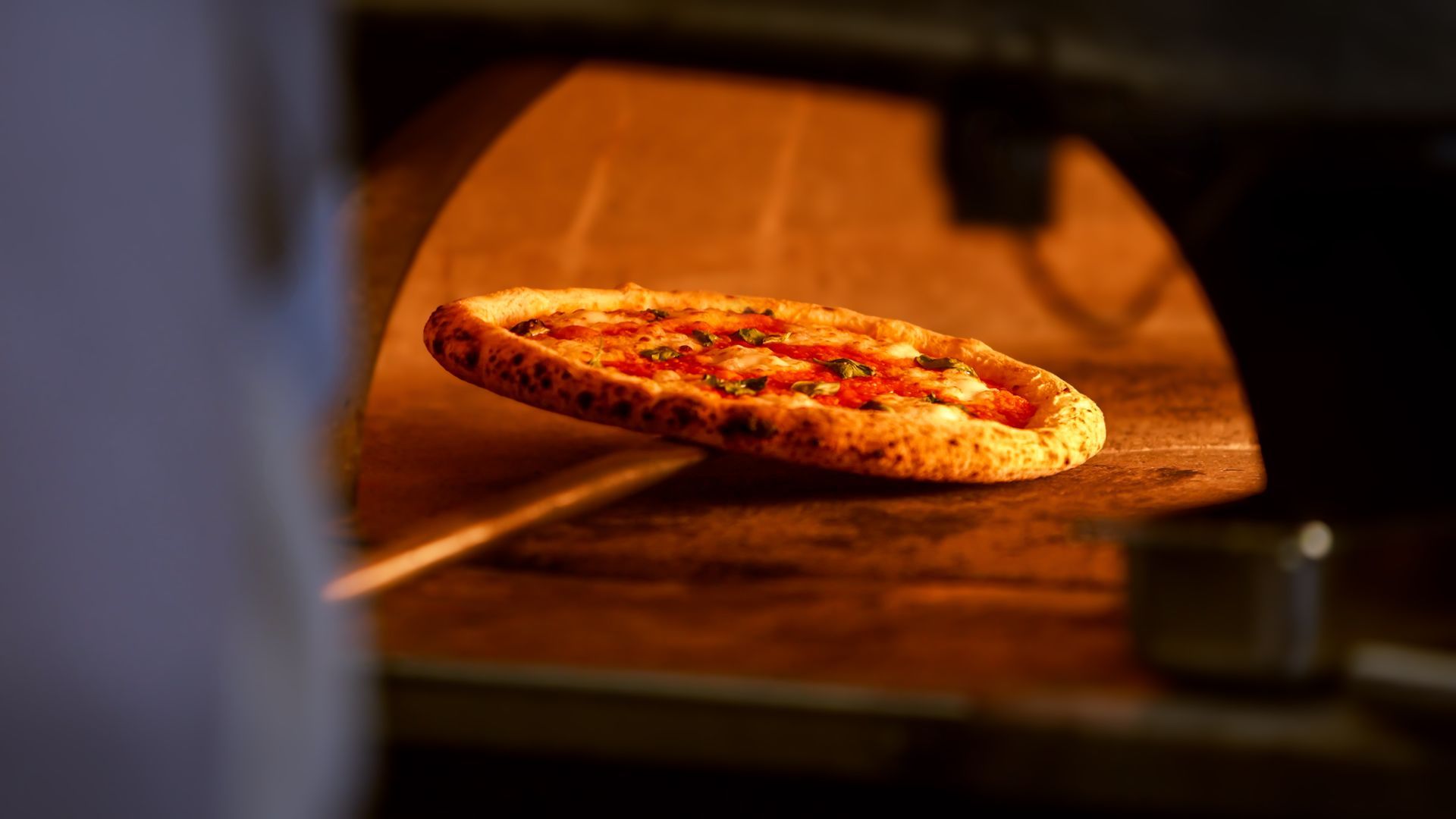Una pizza viene cotta in un forno a legna.