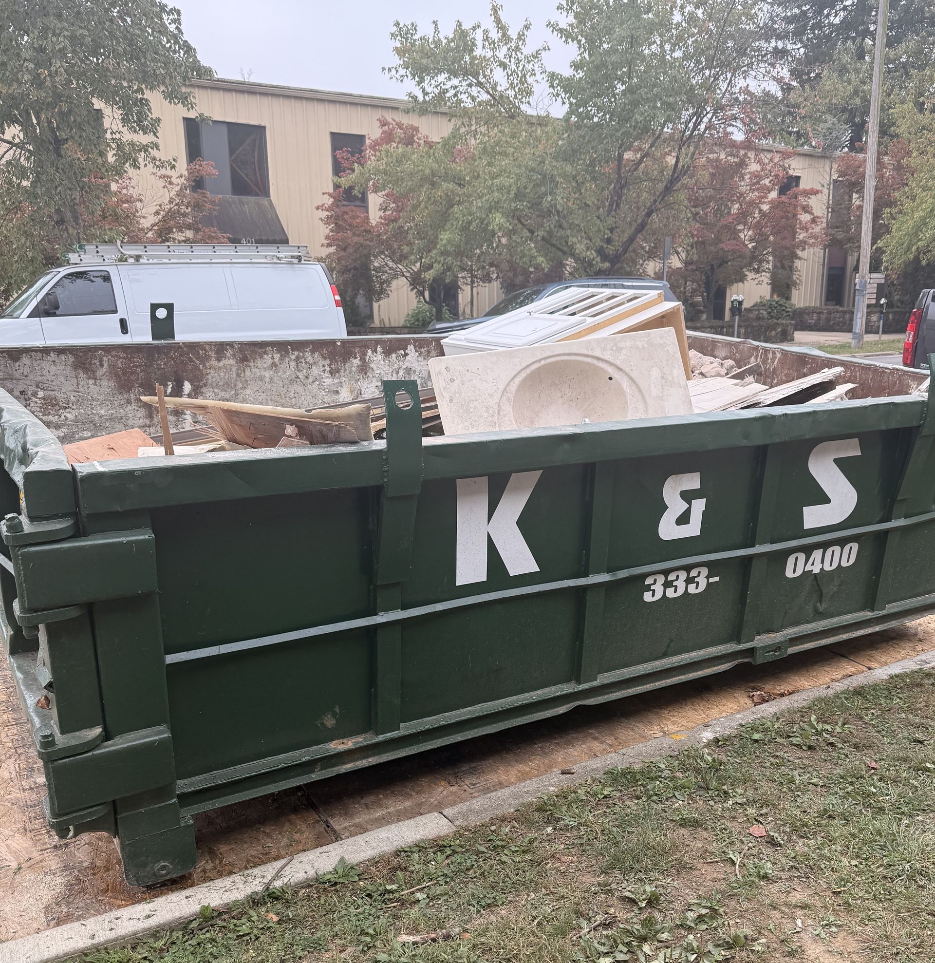 A large green dumpster is parked in front of a store called a center