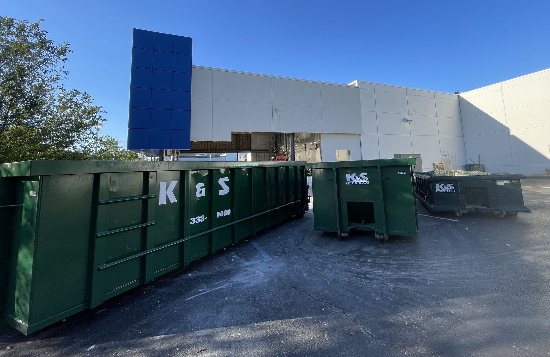 A large green dumpster is sitting in front of a building.
