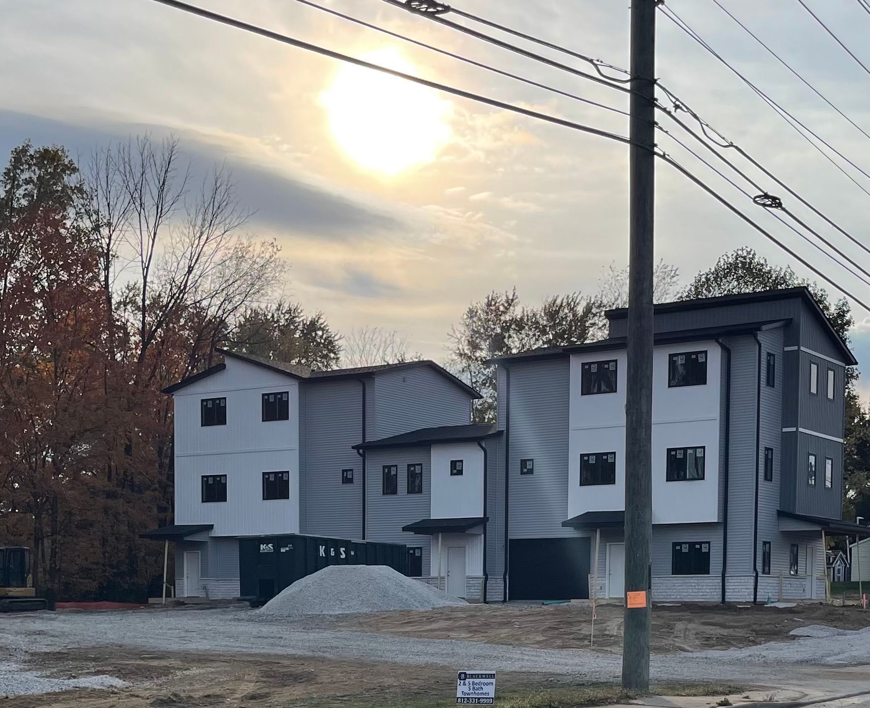 A row of houses under construction with the sun shining through the clouds