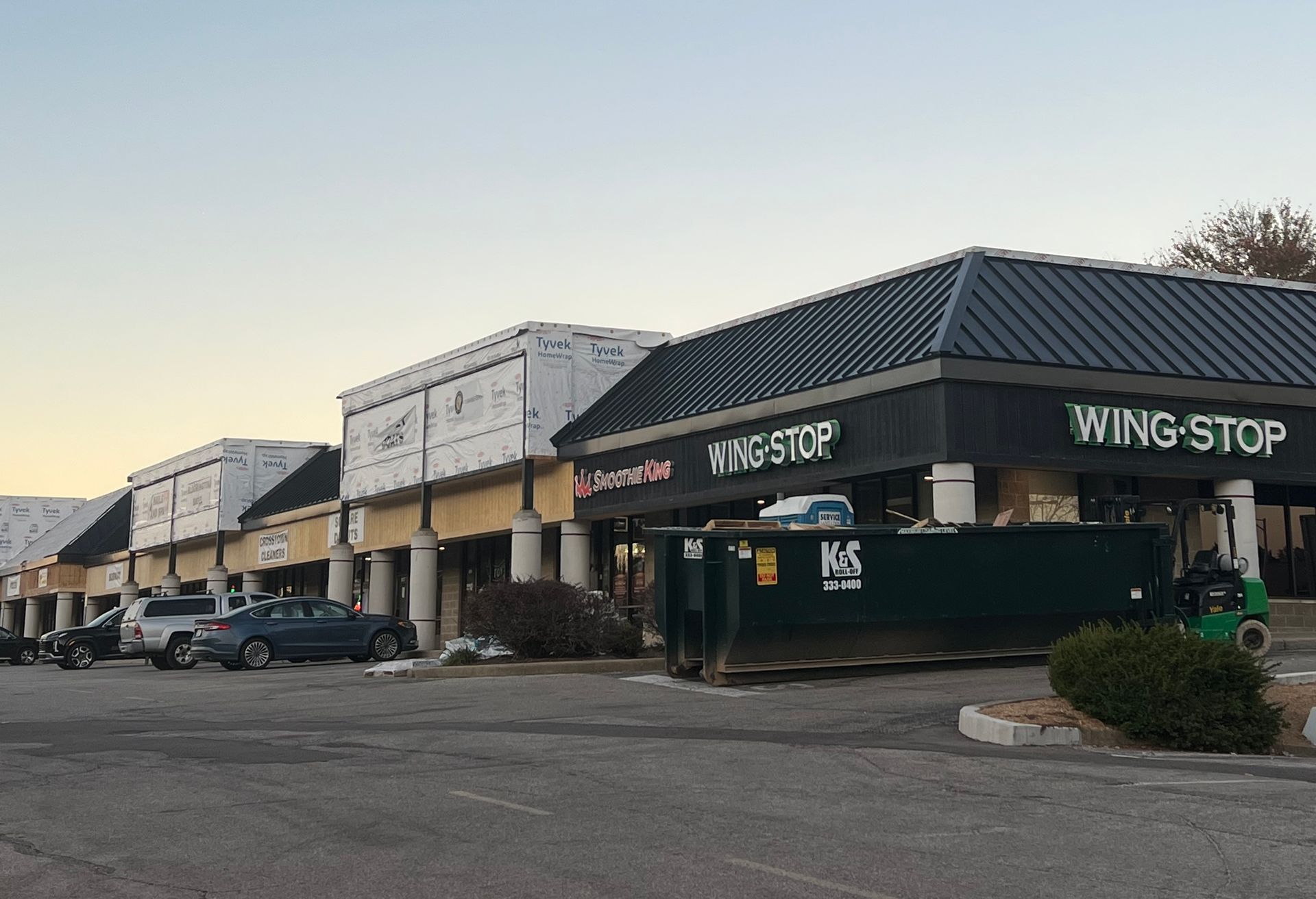 A wing stop restaurant is being built in a parking lot.