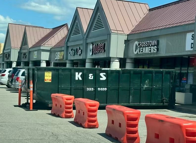 A row of buildings with a dumpster that says k & s on it