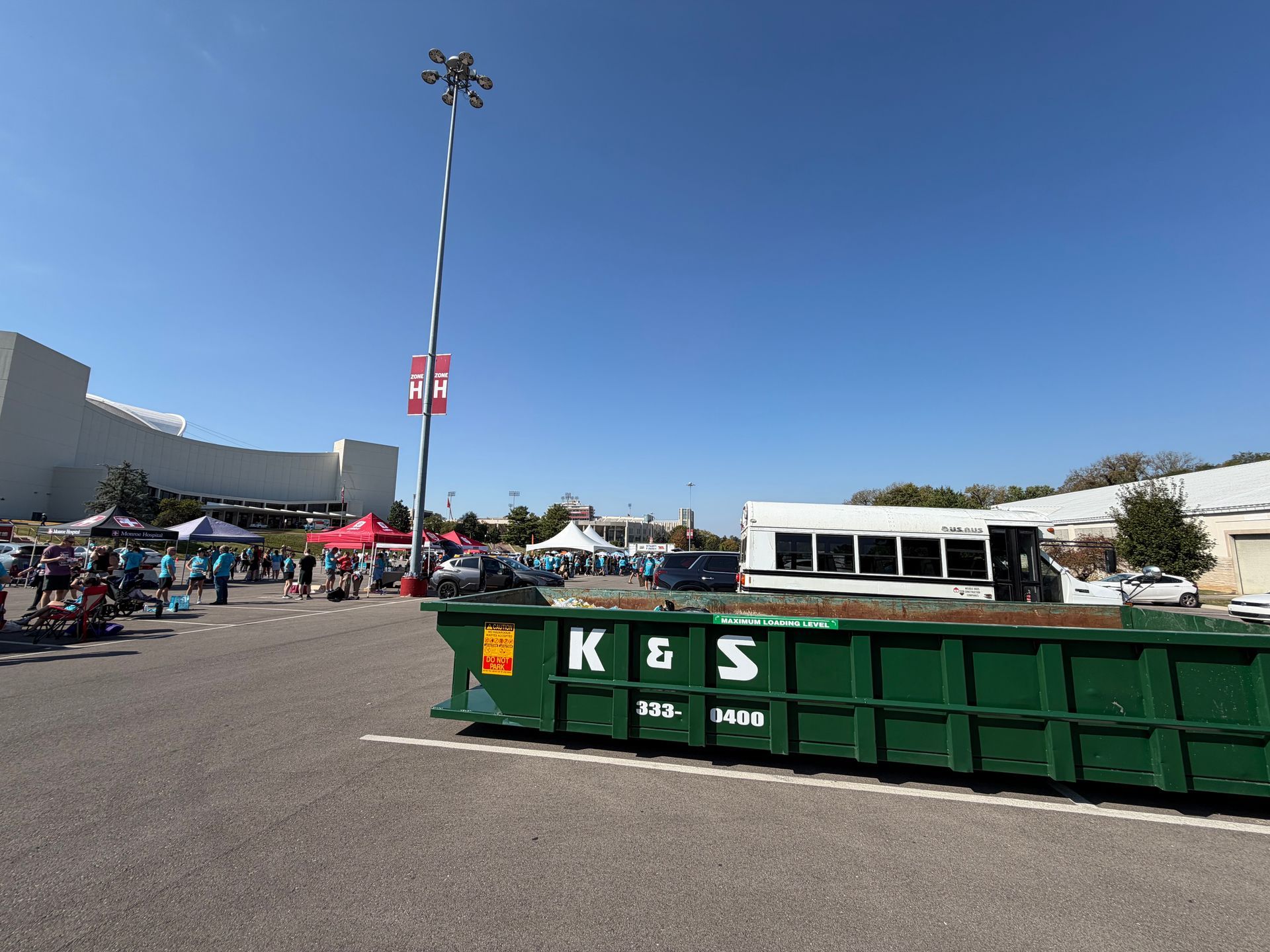 A large green dumpster is parked in front of a store called a center