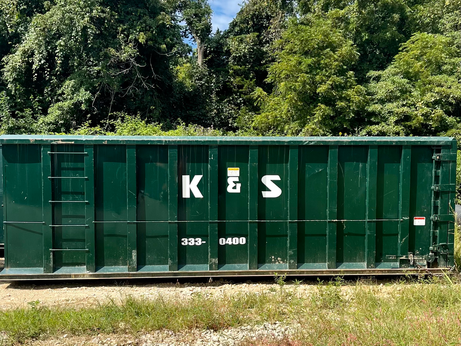 A green dumpster with the letters k & s on it