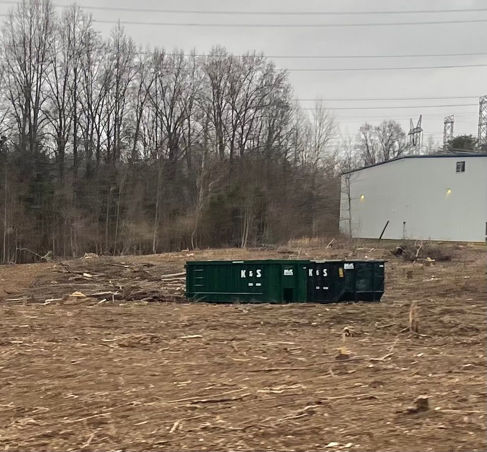 A large green dumpster is parked in front of a store called a center