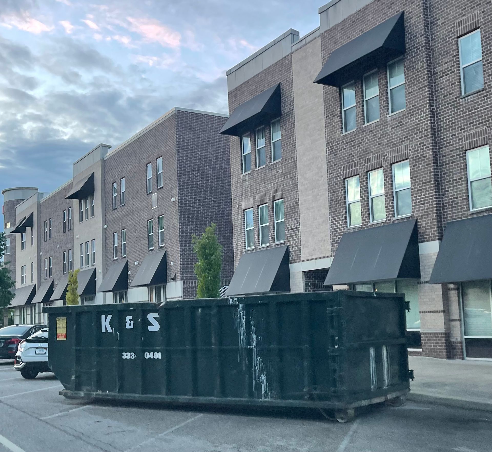 A large green dumpster is parked in front of a store called a center