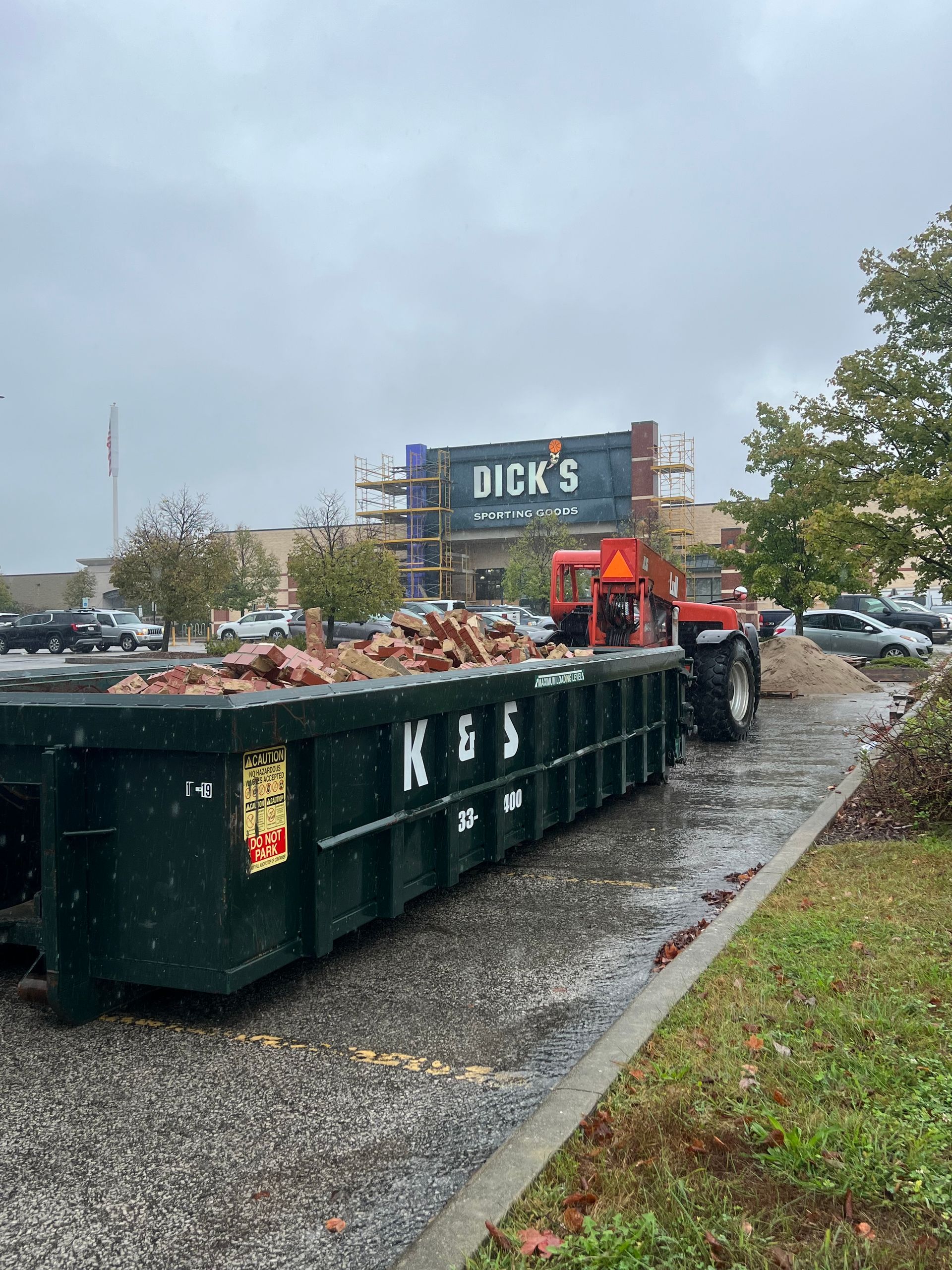 A large green dumpster is parked in front of a store called a center