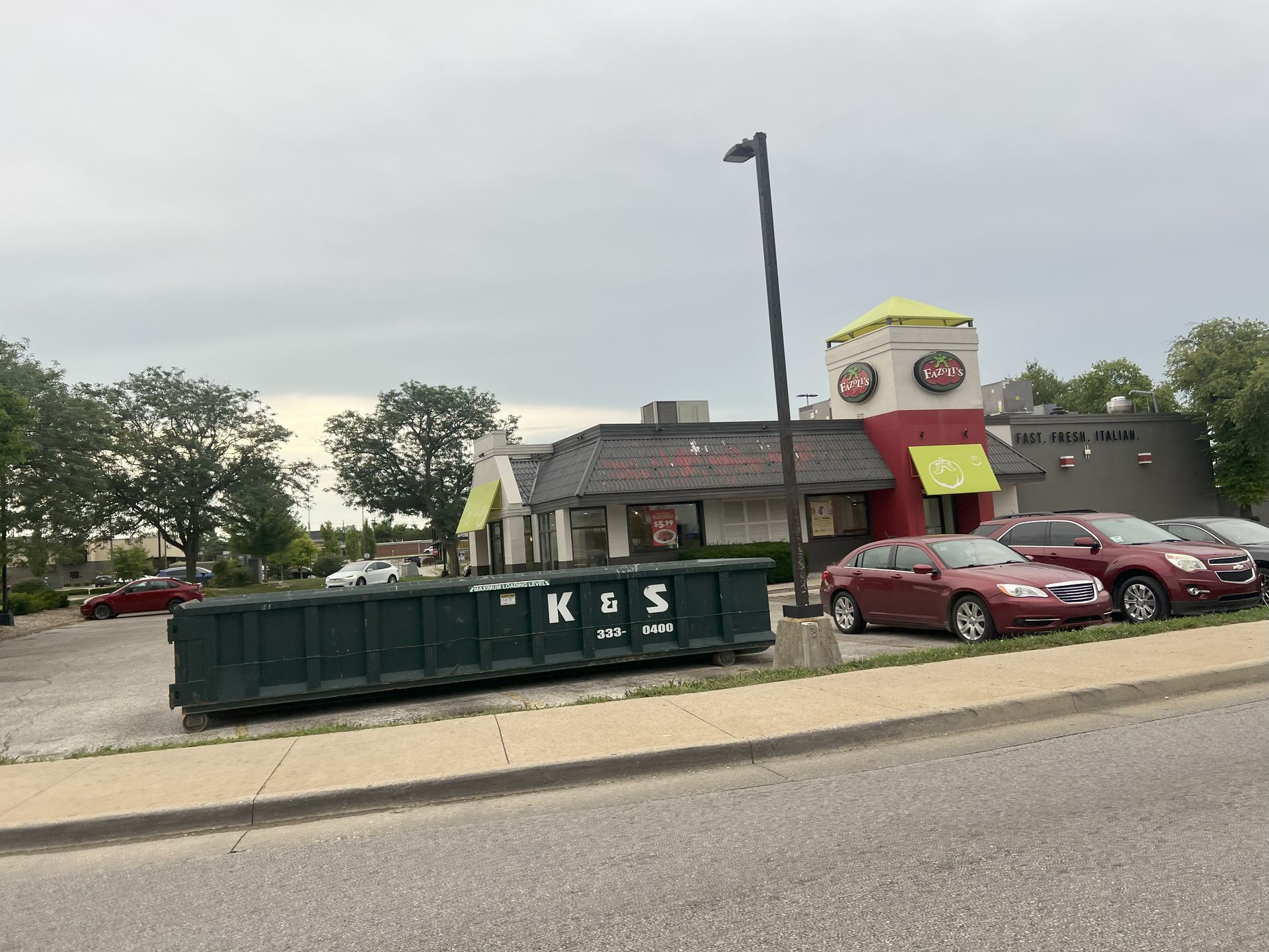 A large green dumpster is parked in front of a store called a center